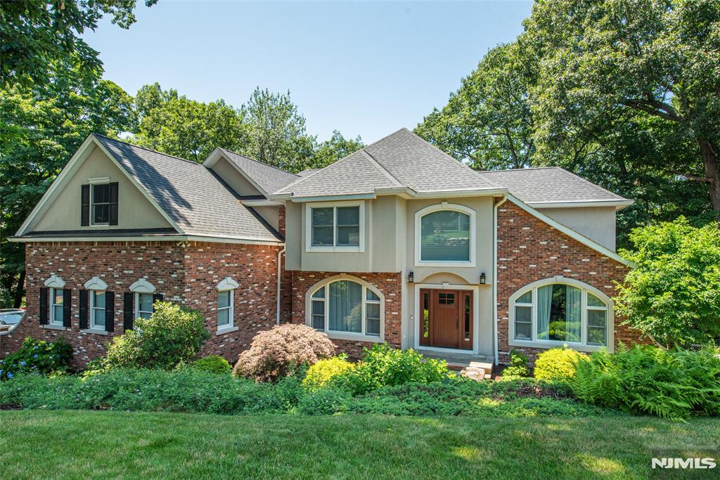 Welcome to this beautifully updated Colonial on 1.38 private acres in the sought-after Kensington Woods section of Ringwood, where mountain and skyline views are seen from every floor. Extensively renovated in 2023 and offering three finished levels of luxurious everyday living. The foyer opens to high ceilings, skylights, and hardwood floors. The showpiece chef's kitchen, refinished in 2023, features granite counters, a Bertazzoni range, wall ovens, wine refrigerator, center island with breakfast bar, and walk-in pantry, opening to the deck and the view beyond. Adjacent are the formal dining room and living room with wood-burning fireplace. A private office completes the first floor. Upstairs, the expansive primary suite is a true retreat, where a bay window with built-in seating nook frames the mountain view, joined by a large walk-in closet and spa-like bath with jetted tub and stall shower. Two generously sized bedrooms share a full bath, with second-floor laundry. The finished walk-out lower level offers flexible private living space with its own separate entrance: a massive open living area with custom wet bar, second washer/dryer, exercise room, full bath, and flex room currently used as a bedroom. Additional highlights: 2023 roof, siding, windows, and maintenance-free gutters, two newer furnaces, newer central air, automatic electronic window shades, oversized 3-car garage, and generous storage. Just over an hour commute from Midtown Manhattan.
