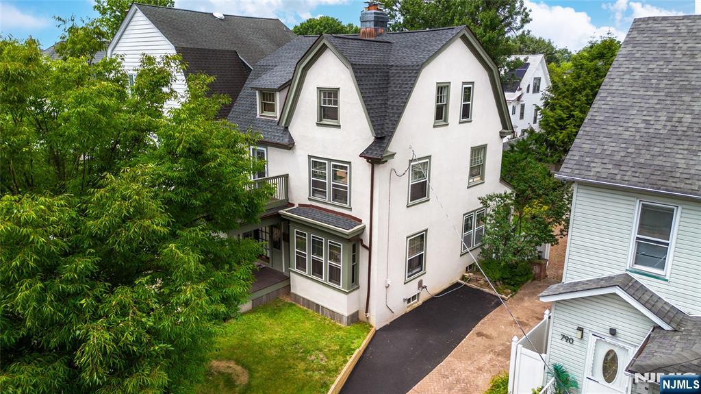 Presence and pedigree define this stately Dutch Colonial Revival, built c. 1920, with its distinctive barn-shaped gambrel roof, large shed dormers, and symmetrical upper windows. Soft sage-green trim in a historically appropriate palette accents the broad covered front porch and second-floor balcony. Inside: gleaming hardwood floors, original wood trim and cornice detailing, pocket doors, and a cozy fireplace. The refinished kitchen features stainless steel appliances, a subway tile backsplash, farmhouse sink, and a convenient powder room. The upper floors offer seven bedrooms, including rooms currently used as a home office and gym, plus two full bathrooms: one beautifully renovated with a glass-enclosed shower and modern vanity, and another featuring a classic clawfoot tub that preserves the home's historic charm. A full basement includes a washer and dryer, an additional half bathroom, and ample storage. Outside: a beautifully maintained, large fenced yard, private covered back porch, wide driveway, and detached garage. Near Branch Brook Park, with easy access to the Light Rail, Newark Penn Station, Route 280, and Downtown Newark.