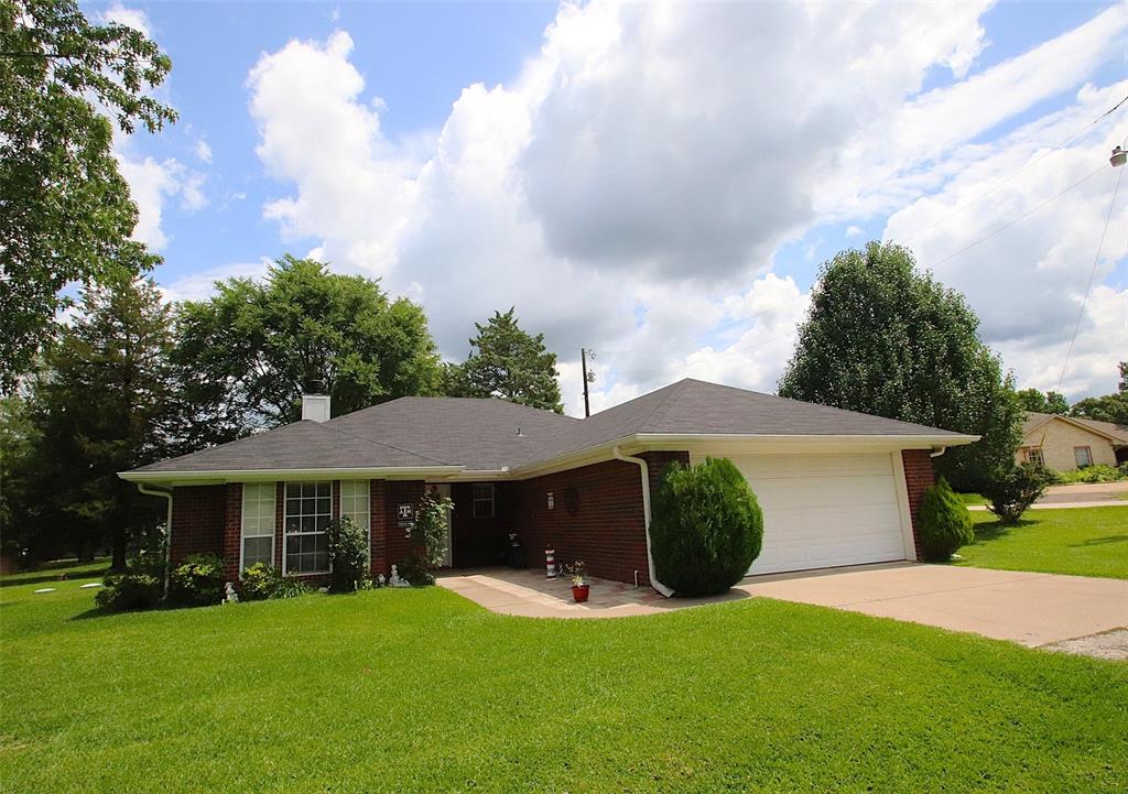 Welcome home to this charming brick beauty tucked away on a spacious corner lot just a stone’s throw away from the peaceful waters of Lake Holbrook! Built in 2002, and almost 1500 sq. feet, this inviting 3-bedroom, 2-bath home offers the perfect blend of comfort, character, and country charm with plenty of space to relax and enjoy life in the country. From the moment you arrive, you’ll fall in love with the welcoming curb appeal featuring a classic white picket fence, covered patio, , mature shade trees, and a convenient, detached carport with a storage room attached. All of these add to the enviable charm of this home. Sitting proudly on a desirable corner lot, this property feels open, airy, and full of possibilities. Step inside and discover a warm and inviting floor plan designed with both comfort and privacy in mind. The split-bedroom arrangement creates a peaceful retreat for the primary suite while offering guests or family members their own comfortable space on the opposite side of the home. Each bedroom is generously sized and filled with natural light, making every room feel cheerful and welcoming. The heart of the home is the spacious living area, perfect for gathering with loved ones, hosting game nights, or simply curling up after a fun day at the lake. It doesn’t happen often in Texas but when it does get really cold, everyone loves a warm fire place and the sound of crackling wood as it burns.  Ceiling fans can be found in all of the bedrooms as well as the living area, keeping the home comfortable year-round while adding a stylish touch to every space. The kitchen and dining area flow beautifully together, creating the ideal setting for home-cooked meals, morning coffee, or holiday celebrations. Whether you’re entertaining guests or enjoying a quiet evening at home, this property offers a relaxed and cozy atmosphere you’ll love coming home to. Please don’t be the one who said, “I should have bought this home”.