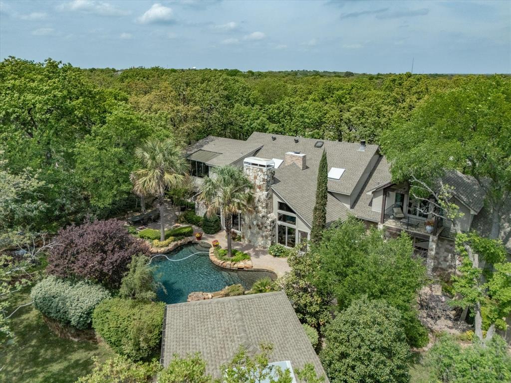 This rustic contemporary lodge estate blends timeless architectural character with refined craftsmanship and is privately situated on nearly four acres beneath a canopy of mature oak trees in the heart of Copper Canyon. A circular drive and expansive covered front porch create a memorable sense of arrival and reflect the home’s impressive estate-scale presence.

Inside, the home is thoughtfully designed around multiple gathering spaces ideal for both entertaining and everyday living. A dramatic library serves as a signature architectural centerpiece, featuring a spiral oak staircase, cherry wood cabinetry and shelving, coffered ceiling, custom illuminated built-ins, and a striking verde granite fireplace. A custom interior kitchen with cherry wood cabinetry, premium appliances, and wine refrigeration anchors the home as a natural gathering space. TWO primary suites offer exceptional flexibility for guests, extended family, or multi-generational living.

Two expansive great rooms, each with its own fireplace & French doors, open seamlessly to the outdoor living areas, while a wall of windows frames scenic views of the landscaped grounds and fills the home with natural light. The outdoor environment functions as a private retreat, highlighted by a PebbleTec saltwater pool and spa, cascading water features, fire bowls, landscape lighting, hand-laid brick patios, and a covered outdoor kitchen and pavilion. Designed for year-round enjoyment, enjoy the media center, premium outdoor stereo speakers, a 3CM granite counter, a translucent, under-lit Onyx bar countertop, plus a propane grill & fireplace. 

This distinctive estate combines privacy, craftsmanship, and a lifestyle centered on entertaining and connection to nature. Ideally located with convenient access to FM 407, I-35W, and I-35E, and just minutes from Lewisville Lake, as well as shopping, dining, and entertainment in Highland Village, Flower Mound, and Denton.  The home is also ~17 miles from DFW Airport.