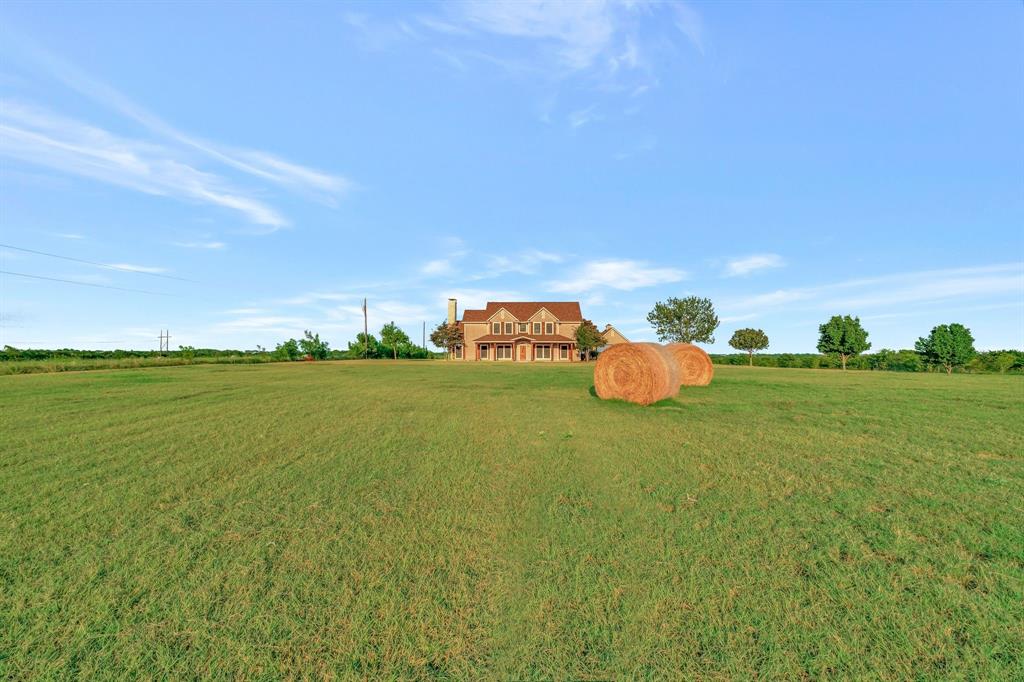 Seller will subdivide! Purchase home and shop on an adaptable 5 to 6 acres. Boundaries to be negotiated.  This gated, 12.51 acre, prairie-style ranchette boasts 10 acres of Coastal Bermuda w 24x60 shop & 3522 sq ft custom home on 2.5 acre homestead. Enjoy watching private planes & gliders @ Midway Regional Airport. Drink in magnificent sunsets & brilliant starry sky on the extended front porch. Springtime surprises w a blanket of bluebonnets & Indian paintbrush. Rustic, cedar pillars & solid Knotty Alder door invite you inside. Stained, glass-paneled, French doors open to a handsome office w access to the primary suite. Expansive two-story living w vaulted ceiling & Austin stone gas-log fp-an entertainers' delight! Wood flooring in living, dining & entry. Commercial kitchen impresses w Imperial stainless steel, gas, 6-burner stove, 24x24 griddle & 2-36 in. full-sheet ovens & custom, commercial vent-a-hood. Custom solid wood cabinets, & commercial frig space, too. Massive commissary or craft room off kitchen. Snuggle up to the flicker of the 2nd stone fireplace in the primary suite. Ensuite bath renovated w freestanding soaking tub w waterfall faucet, solid wood vanities w Carrara marble countertops, ceramic, apron sink & walk-in shower. Utility boasts extensive upper & lower cabinets, sink, bonus counter prep space, & ice machine! Built-in ironing board & electric or gas dryer hook up!
Three large secondary bdrms enjoy attached bath & ceiling fans. Substantial flex room includes built-in desk, fan, and cabinets.
1460 sq ft insulated shop w steel frame construction & 12 in. slab, 2 entry-bay doors w add'l interior bay door to create 20 ft section. Full electrical, overhead lighting. Stubbed for water in the 20 ft section. 2 hose reels. Slab-mounted compressor behind building. Four-rail pipe fence, swing gate entry & remotes. Barbed wire perimeter fencing. 40-yr, inpact resistant fiberglass reinforced comp shingles. Historic site of Superconducting Supercollider!