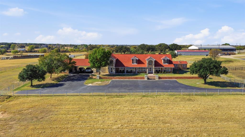 Experience true ranch living on this 66.65± acre cutting and cow-horse property located just north of Springtown. This ranch is fully set up for training, livestock, and multi-residence living, offering a rare combination of space, function, and comfort. 

The main 6,449 sq ft ranch-style home features 6 bedrooms, 4.5 baths, multiple living areas, two primary suites, an office, sunroom, and a large family room with vaulted ceilings and fireplace. The gourmet kitchen includes Sub-Zero appliances, large island, and extensive cabinetry. Additional features include a wet bar with margarita machine with a wolf beverage refrigerator, security system, storm shelter, laundry room, and an attached 3-car garage with porte-cochere.

Step outside to a pool and hot tub, outdoor kitchen, fenced yard, sprinkler system, and both city water and private well water. A 500-gallon owned propane tank also services the home.

The property is fully fenced with 5-rail pipe fencing and is designed for serious horse, cattle, or ranch operations. Improvements include a 46’x100’ horse barn with runs, office, tack room, wash bay, med room, laundry, and small apartment; a mare motel (26’x100’); covered arena; Priefert horse walker; and covered cattle working pens with squeeze chute. There are 8 separate pastures and pens, 10 turnout shelters, an 8-bay insulated equipment and hay building (46’x100’) with automatic doors, plus a 30’x60’ RV and trailer garage with automatic doors.

The land offers open pasture, coastal Bermuda, a 1-acre lake with dock, three stock tanks, and beautiful views across the acreage as well as lots of room to feedlot practice cattle. The property also includes a 2017 Fleetwood 2 bed - 2 bath mobile home ideal for hired help or guests.

With multiple barns, shelters, storage buildings, arenas, working pens, and AG exemption already in place, this property is ready for cattle, horses, training programs, or multi-use ranching.
