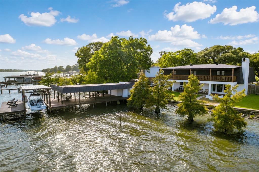 Fabulous Lakefront Retreat boasts stylish finishes, fantastic lake views from almost every room in the house and an AWESOME BOATHOUSE with tons of covered sitting and entertaining space, boat slip with automatic lift, additional covered slip, and dock storage building. This beautifully updated home features 5 spacious bedrooms, 3 bathrooms, and a large game room perfect for entertaining. NEW WINDOWS, NEW ROOF, NEW BATHROOMS, NEW PAINT, ALL NEW FINISHES, RECESSED CAN LIGHTING, NEW LIGHT FIXTURES, NEW FLOORING (hard surface flooring throughout).Living Room features a wall of windows, stone wall, and gas fireplace. Huge upstairs Game Room with cork wall. 2 full downstairs baths with custom tile flooring, custom tile tub surrounds, walk-in shower with glass door, designer mirrors and plumbing fixtures. Kitchen is stylish and functional - black and white checkerboard tile floors, open shelving, designer lighting, and loads of cooking and serving space. Appliances are stainless steel and modern. Wonderful laundry room features a built in coffee bar area with sink and beverage fridge. 4 upstairs bedrooms, 1 downstairs bedroom with private bath. Great closets. Adorable custom flower tile in sizable upstairs bath with double vanities, custom walk-in shower, and free-standing tub. Easy access to boating, fishing, and waterfront recreation. First and second story porches overlooking the lake plus a sizable yard. Whether you're looking for a full-time residence, weekend getaway or wonderful investment opportunity, this exceptional property combines comfort, space and the best of lakefront living.
