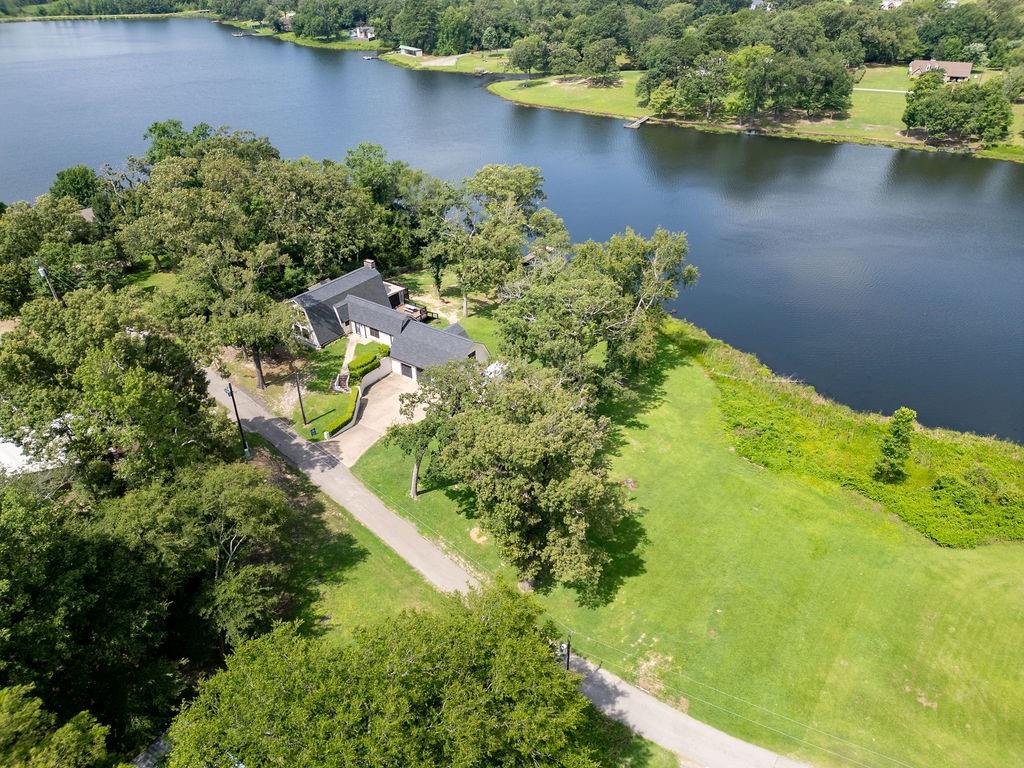 Tucked away on a private, stocked lake, this rare country cottage offers the kind of peaceful waterfront living that’s getting harder and harder to find. Bass, catfish, and crappie fill the water, and your days can be spent fishing from the brand-new 40-foot pier with a 10x12 landing, completed in January 2026. The setting is truly serene—watch otters, ducks, herons, and even pelicans drift across the water, all while enjoying unforgettable sunset views over the lake. Inside, the home offers 4 bedrooms and 3 full baths with a flexible, well-designed layout. The primary suite is located on the main level and features a beautifully updated en-suite bath added in 2024. A second private suite upstairs provides excellent space for guests or multigenerational living. Two additional bedrooms are located downstairs, one currently used as a home office. Designed for both comfort and entertaining, the home features a spacious sunken living room with a brick fireplace and a large dining area positioned to take in sweeping lake views—perfect for hosting family and friends in every season. Outdoor living is just as impressive, with two back decks including a large partially covered deck with a screened-in sitting area ideal for year-round enjoyment. The 1.2-acre property transforms in spring and summer into a lush, manicured, park-like setting that feels almost like a private golf course. Additional features include an oversized attached garage and a 10x20 lofted storage building with double doors, windows overlooking the lake, and excellent potential as a workshop, studio, or hobby space. Conveniently located just 10 minutes to Mineola or Quitman, 20 minutes to Lindale, and about 35 minutes to Tyler, this property offers the perfect balance of privacy and accessibility. A peaceful lakefront retreat with space, updates, and unmatched views—this one is truly special.