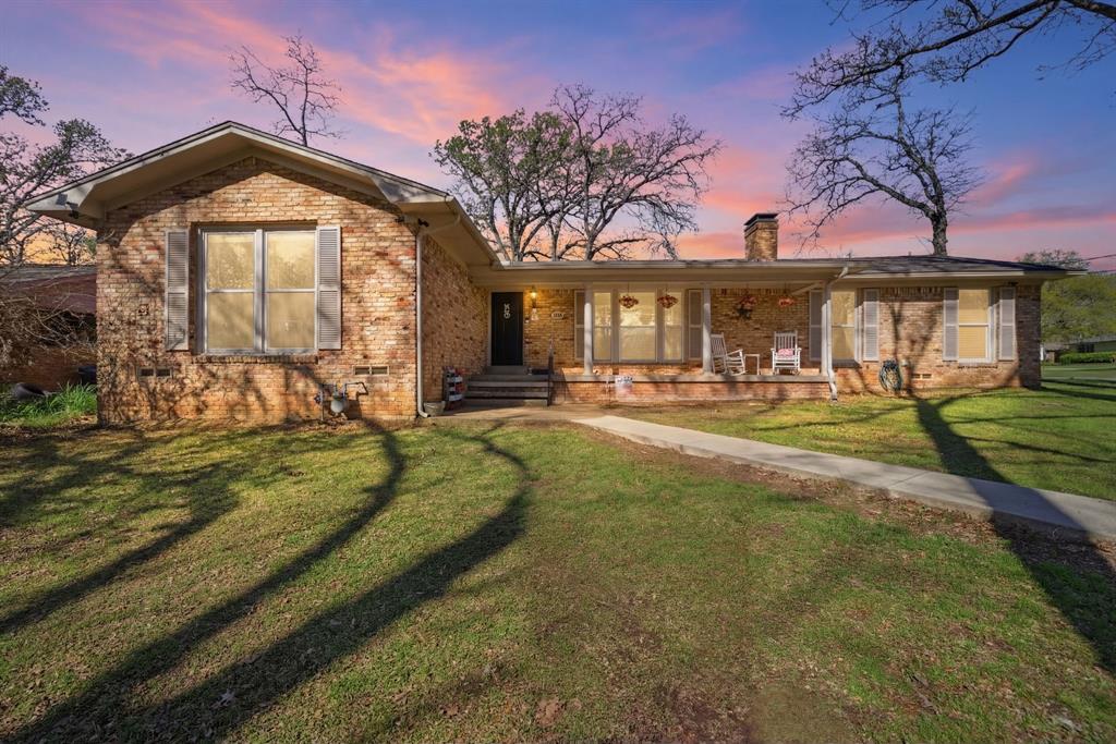 Situated on 0.46 acres corner lot, this 2,021 sq ft 3 bedroom, 2 bathroom home offers inviting spaces, thoughtful updates, and a layout that gives you room to spread out. Step into a welcoming living room filled with natural light, anchored by a fireplace, convenient built-ins, and natural hardwood floors that add warmth and character. The updated kitchen is designed for both everyday living and easy hosting with granite counters, coffee nook, gas range, built-in microwave, breakfast bar for busy mornings on the go, and windows overlooking the backyard. The dining room opens to the outside with double doors to the covered patio. The primary bedroom creates a comfortable retreat with abundant natural light, spacious walk-in closet, and updated bathroom. Secondary bedrooms offer spacious closets, hardwood floors, and plenty of lighting. A bonus second living area with its own mini-split, outside patio access, large storage closet, and soundproof door adds exceptional flexibility. Outside, enjoy a covered patio (2024), mature shade trees, fencing (2019), two storage sheds, and the confidence of an updated roof (2016). This home offers East Texas charm in a town known for its rich heritage. Proudly Claim Your Piece of Texas!
