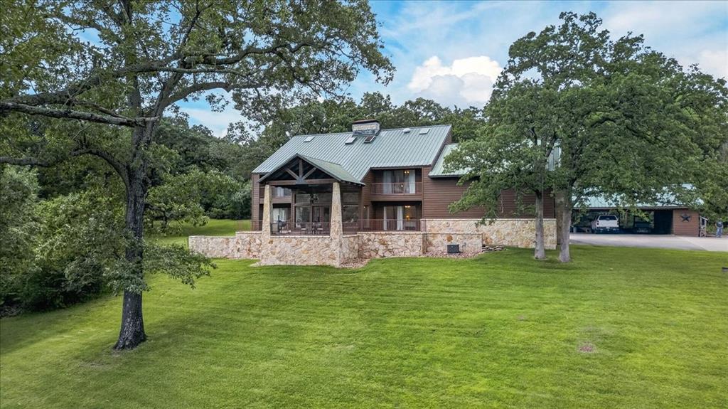 Tucked beneath a canopy of mature hardwoods on 10.08 secluded acres, this East Texas estate offers a rare combination of privacy, natural beauty, and custom craftsmanship just minutes from Athens. Spanning over 4,700 square feet, the cedar home is perfectly positioned among heavily wooded surroundings, creating a peaceful retreat where nature and luxury come together. Inside, soaring vaulted ceilings, expansive living spaces, and walls of windows showcase stunning views of the surrounding landscape. The thoughtfully designed floor plan features 4 bedrooms, 4 full baths, 1 half bath, multiple living areas, office space, & flexible gathering areas ideal for entertaining family and guests. The spacious kitchen is designed for both function and hospitality, with granite countertops, large center island, builtin refrigerator, double ovens, abundant cabinetry, breakfast bar, pantry, and generous prep space. The dining and living areas provide a warm and inviting atmosphere highlighted by wood accents, stonework, and a wood-burning fireplace. The primary suite offers a private escape with wooded views, dual vanities, garden tub, separate shower, linen storage, and a large walk-in closet. Additional bedrooms provide comfortable accommodations for family and visitors.Outdoor living is equally impressive with covered patios, elevated decks, and peaceful spaces to relax while enjoying the sights and sounds of nature. A scenic creek winds through the property, enhancing the park-like setting and attracting abundant wildlife. The acreage provides room for recreation, gardening, hiking trails, or simply enjoying your own private sanctuary. Additional improvements include a detached three-car carport, storage building, sprinkler system, metal roof, city water, septic system, and high-speed internet availability. The property is heavily wooded, offering exceptional privacy while remaining conveniently located near shopping, dining, schools, medical facilities, and Cedar Creek Lake.