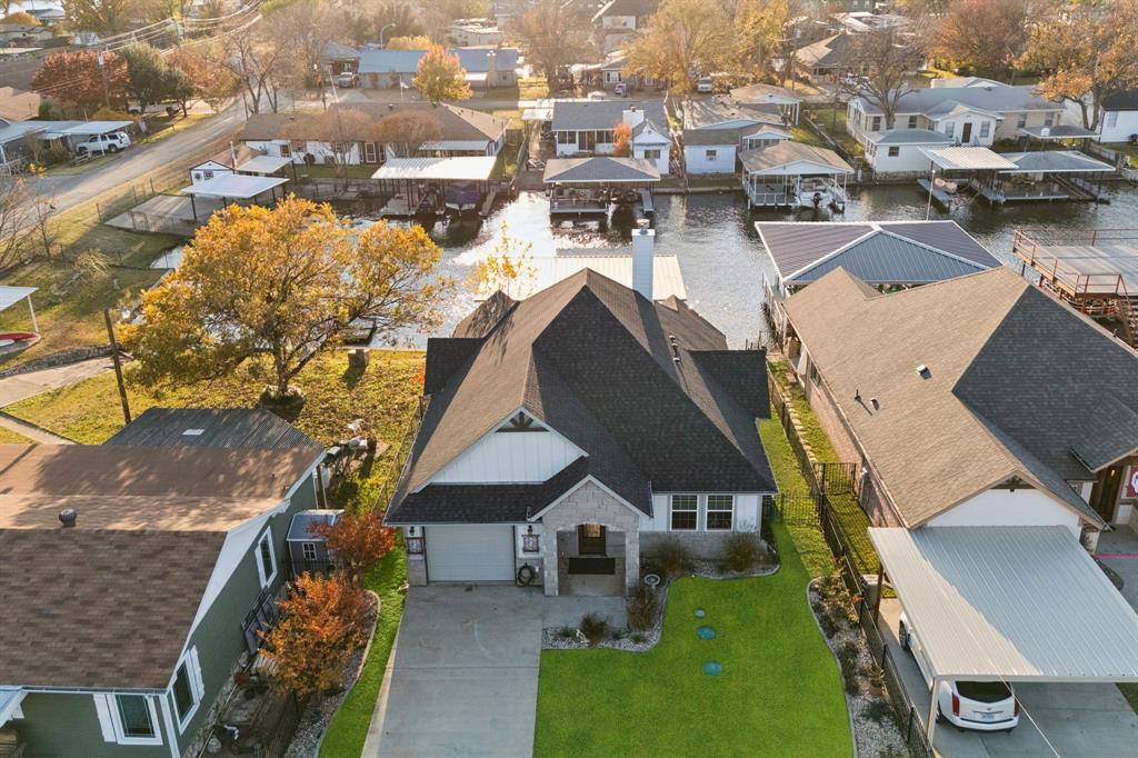 Waterfront Perfection Meets Effortless Living in Ports O’ Call. Experience turnkey lake living in this stunningly constructed waterfront retreat on Lake Granbury. Designed with a rare commitment to full accessibility, this home features a seamless, step-free interior and a direct, smooth path from the back door to your private boat dock and lift. The open-concept floor plan is anchored by a dramatic floor-to-ceiling stone fireplace and durable vinyl plank flooring with gorgeous natural light beaming through. A chef-inspired kitchen boasts black granite countertops, custom white cabinetry, and a large social island. The primary suite serves as a true sanctuary with vaulted beam ceilings and ensuite bathroom with accessible shower. A guest bedroom with en-suite bath sits in the front of the home and creates privacy from the living and kitchen areas. Situated on a constantly flowing canal with quick main-lake access, you are just a short cruise from Granbury’s historic square and local favorites like Stumpy’s. Automatic driveway gate, metal fencing, sprinkler system, and lake pump. Boat, golf cart, and kayaks are available with acceptable offer.
