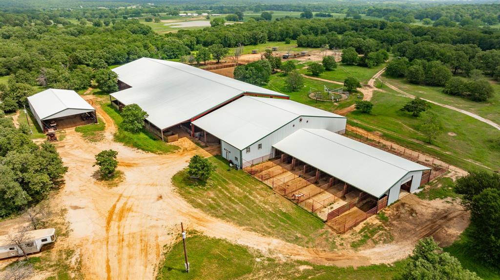 Only an hour and fifteen minutes to Will Rogers Memorial Center in Ft Worth, this turn-key facility lies on 281.5 acres. The 275x125 arena stands as the crown jewel, equipped with a sprinkler system and roping chutes that seamlessly transition to a cowhorse arena. The attached show barn boasts 14 stalls with runs that effortlessly transform into 28 stalls with a simple adjustment of a gate. Just behind the covered arena is a 125x125 cutting pen complete with cattle holding pens, ensuring efficiency in your day to day. Ten holding pens are located behind the arena with an alley system. Attached to the arena is an expansive office with a full kitchen, half bath, and above the office is a two bedroom apartment. The main home features four bedrooms, 3.5 bathrooms, an office and game room. Just off the master suite, the balcony overlooks the pool and outdoor kitchen area. An insulated shop with power, water, and an apartment is one of 3 additional living quarters. All of this and more!