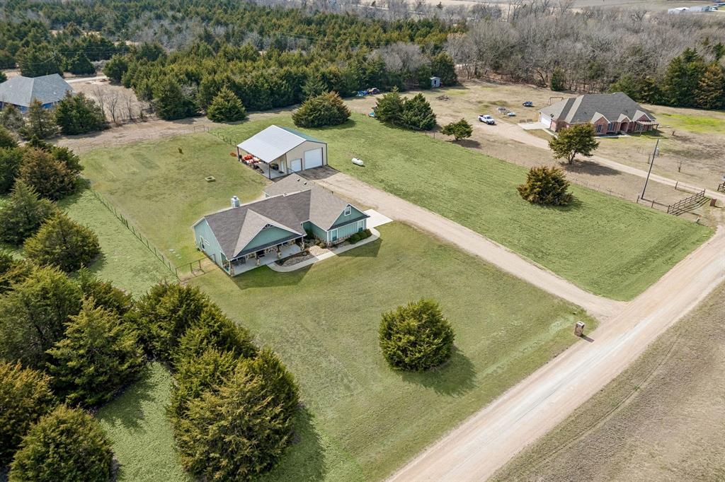 This beautifully designed 3-bedroom, 2-bath home sits on 2.781 acres and offers 1,963 square feet of upgraded comfort and style in a peaceful country setting. From the moment you walk through the gorgeous iron front door, you’ll notice the attention to detail throughout, including stunning stained concrete floors, quartz countertops in every space, and custom cabinetry paired with stainless KitchenAid appliances. The spacious living area features a cozy propane-igniting wood-burning fireplace, perfect for relaxing evenings. The luxurious primary suite is a true retreat, complete with a spa-like bathroom showcasing a massive walk-in shower, a freestanding soaking tub, and separate his-and-hers closets with convenient access to the laundry room. Recent upgrades include a new roof, gutters, and garage door (2026), along with the added peace of mind of a whole-home Generac generator. Outside, you’ll find a large lot with a fully fenced backyard and an impressive 30x40 insulated, climate-controlled metal shop—complete with an 8-foot pool table, making it the perfect space for entertaining, hobbies, or a workshop. Situated in a quiet neighborhood where side-by-sides and horses are welcome, this property offers the perfect blend of comfort, functionality, and country living.