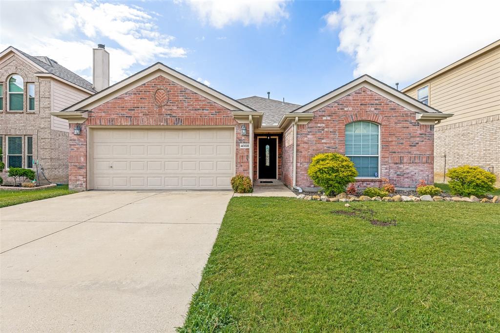 Welcome to 4008 Drexmore Road, a well-maintained single-story brick home with an inviting open layout and easy-care finishes throughout. The spacious living room features vaulted ceilings, warm wood-look flooring and a corner fireplace, creating a comfortable gathering space that flows naturally into the kitchen and dining areas. The kitchen offers abundant cabinetry, generous counter space, a center island, gas cooktop, tile backsplash and a nearby pantry. The private primary suite includes a vaulted ceiling, large walk-in closet and an updated bath with dual sinks, soaking tub and separate tiled shower. Secondary bedrooms also feature wood-look flooring and ceiling fans, providing flexible space for family, guests or a home office. Additional highlights include crown molding, recessed lighting, a separate laundry room and tile flooring in the kitchen, dining and wet areas. Outside, the classic low maintenance siding exterior is complemented by established landscaping and a covered back patio that extends the living space outdoors. The oversized two-car garage features a durable epoxy floor and offers excellent parking and storage. Conveniently located in North Fort Worth with access to nearby shopping, dining and major roadways, this home combines practical design, comfortable living and everyday convenience.
