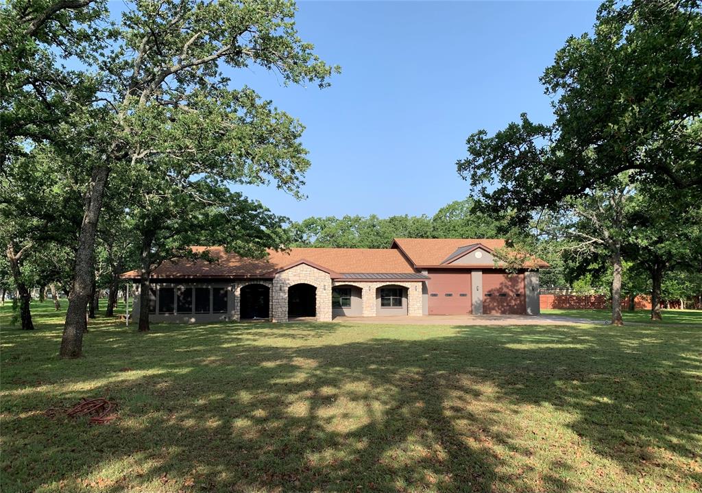 Located on approximately 1.4 wooded acres near Lake Graham, this 4-bedroom, 4-bath custom home reflects Texas Ranch architecture with Hill Country design elements, offering a balanced blend of space, comfort, and thoughtful design suited for both everyday living and hosting.
The open-concept living and kitchen area serves as the central gathering space, featuring a beamed ceiling, built-in electric fireplace with custom shelving, and a generously sized island with updated appliances. The home is all-electric and includes a new 5-ton HVAC system (under warranty) and an energy-efficient water heater.
A light-filled sunroom or second living area provides flexible use and easily functions as a dining space, with expansive windows overlooking the wooded setting—well-suited for gatherings or quieter evenings.
The split-bedroom layout offers privacy, with each bedroom featuring its own ensuite bath and walk-in shower. The primary suite includes a spacious bath and a walk-through closet with built-ins and a dedicated vanity area.
Additional interior features include 10-foot ceilings, ceiling fans throughout, ample storage and closet space, a wet bar with refrigerator in the hallway, a full-size utility room with washer and dryer, and a 4th bedroom or office with front-facing views.
Exterior features include a recently updated septic system, multiple exterior water faucets for irrigation, a 220V outlet in the sunroom, and additional storage above the garage. Ft. Belknap Co-Op Water.
The attached garage offers oversized doors and practical space for vehicles and storage.
A peaceful, wooded setting, mature oak trees with convenient access to town and no city taxes completes the property.