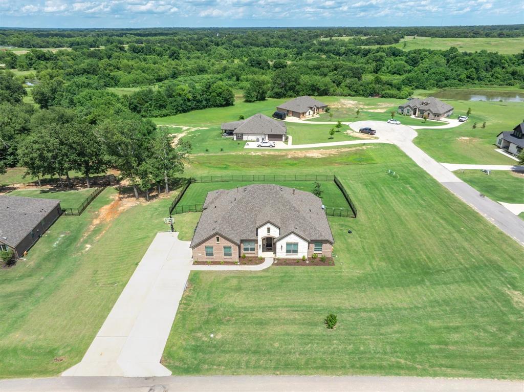 Spacious 2,735 SF 4-bedroom home with 2 living areas, office, and enlarged driveway for multi parking on a premium 1-acre corner lot in Edgewood ISD, tucked on a quiet corner of two cul de sacs with wide-open horizon views. Built in 2023, this open-concept home features soaring 12-foot ceilings, tall doors, neutral colors, and low-maintenance LV plank flooring. The bright white kitchen includes quartz countertops, a large breakfast-bar island, gas cooktop, convection oven, and glass-front cabinetry, with windows across the back of the home filling the space with natural light and showcasing the hilltop setting. The private split primary suite offers peaceful views, an ensuite bath with soaking tub, walk-in shower, dual vanities, and a generous walk-in closet. Three secondary bedrooms are located on the opposite side of the home, with a full bath that offers two separate vanities to make mornings easier. A separate office with glass doors sits off the main living area for work or study. A second living area makes an ideal game room, teen retreat, media room, or flex space, with a convenient half bath nearby. Additional features include can lighting, tankless water heater, a covered back patio ready for your grill, iron fencing, basketball goal, and an extra-large double driveway that can accommodate 6–8 cars, with more yard extending beyond the fenced area. Located in a neighborhood of attractive homes on large lots in the sweet town of Edgewood, this property offers a country feel while still being close to major routes and just minutes from I-20 for easy commuting and access to nearby amenities.