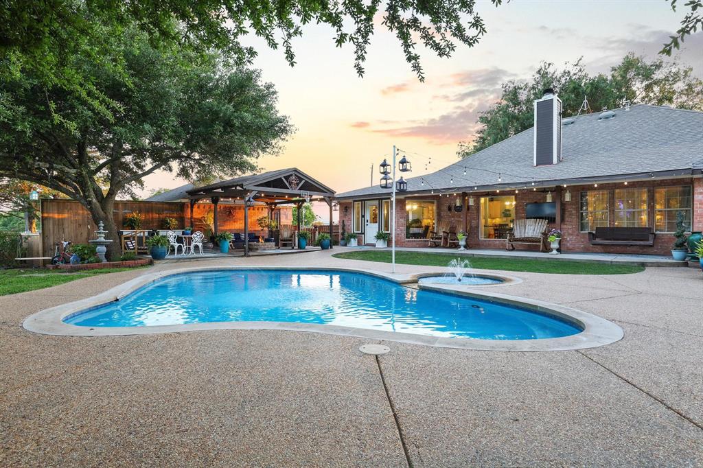 Welcome to paradise. Nestled on 5 unforgettable creekside acres, this gorgeous property offers the perfect blend of acreage and comfortable elegance. The show-stopping pool and outdoor living spaces deliver a magazine-worthy entertaining experience. This single-story brick home is cherished by its original owner & offers a thoughtful, flexible floor plan. Step inside to find stunning architectural archways that define the living area, creating a visual delight. Relax by the inviting, cozy fireplace, the perfect heart of the home. Large windows offer beautiful views of the pool & gardens. The kitchen is spacious, light, bright, loaded with custom cabinetry, granite counters & lighting to accent the finest details. Formal dining AND casual dining in the kitchen! Coffee bar is a work of art, the butler's pantry is fantastic. Primary BR is spacious, the spa inspired ensuite is incredible! Beautiful cabinetry, dual sinks, backlit mirrors, stunning shower, the jetted tub & fireplace offers a resort style experience. Four additional BR provide flexibility, rounded out with a full & half bath. The ultimate backyard oasis is designed for luxurious living & entertaining! The stunning property features a centrally located pool surrounded by multiple, spacious patios & an enchanting covered arbor for al fresco dining. The detached, fully equipped guest quarters offer a charming porch, full kitchen, bedroom, bath & private office space, perfect for hosting or remote work. Additional highlights include a serene second patio for intimate firepit gatherings & a large, secure pet run. This is a rare, perfectly manicured retreat! Lush trees, tank with a water feature & a dock, there's no end to the outdoor beauty this property provides. Located in competitive Trenton ISD, great location, easy access to shopping, restaurants & main thoroughfares. The grounds resemble a movie set, if you love hosting & entertaining, this property has it all!