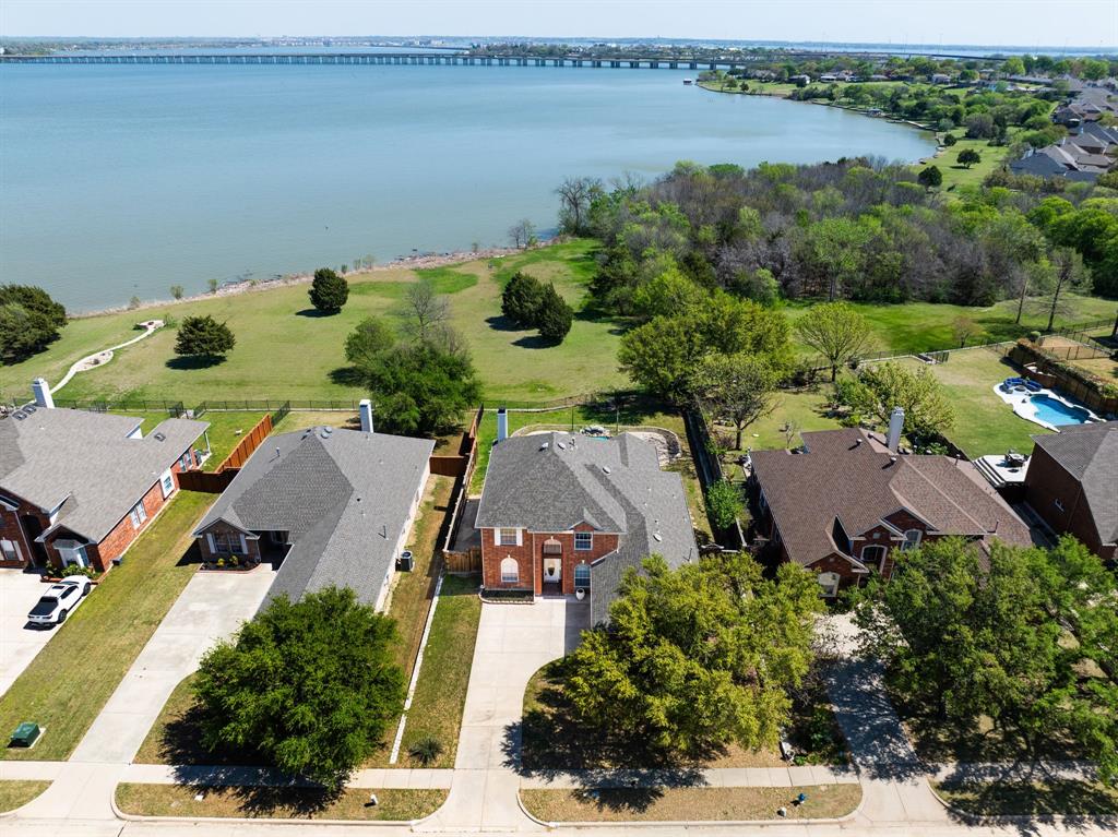 Rare opportunity to own 75 feet of lake frontage inside a gated community with sweeping water views & 
direct access to the city owned shoreline. This lakefront home offers the lifestyle buyers dream about, 
peaceful mornings by the water & unforgettable evenings poolside with family & friends. Inside, 
engineered hardwood floors lead you through an open layout featuring a private study with dramatic 
midnight blue built ins & rolling library ladder, an elegant formal dining room, & a light-filled living area 
framed by a wall of windows overlooking the pool & lake, dressed with electric shades. The beautiful 
kitchen is fully equipped with granite countertops, white cabinetry, travertine backsplash, new 2026 gas 
cooktop, new 2026 wall oven plus convection air fryer microwave combo, Stainless Fridge that remains 
along with walk in pantry. The primary suite captures tranquil lake views & includes a rainfall showerhead, 
separate garden tub, dual sinks, & oversized walk in closet. Upstairs offers a loft, spacious game room 
with lake views, & large secondary bedrooms. The backyard is designed for entertaining with a covered 
patio, play pool with water feature, mature oak tree, grassy yard, wrought iron fencing for unobscured 
views, & private gate access to the lakefront. A true waterfront gem in a convenient location. FULL 
FEATURES LIST AVAILABLE