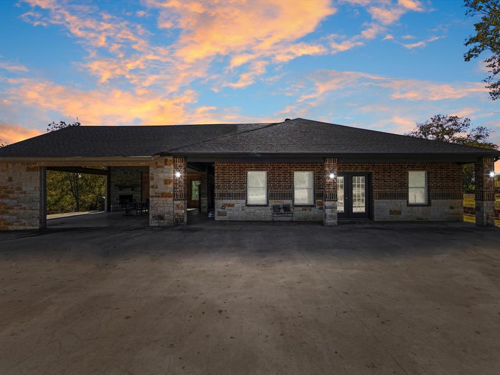 Discover true country living on nearly eighteen acres of wooded beauty in Kemp, Texas. This private rural homesite offers a peaceful setting with a long gated driveway, mature trees, and a picturesque pond that greets you as you enter the property. The land is mostly wooded, giving you natural privacy and endless opportunities for recreation, livestock, hunting, or future expansion. The home is designed for comfort and easy living, featuring an open-concept layout with wood-look tile throughout, neutral finishes, and plenty of natural light. The living area flows seamlessly into a spacious kitchen equipped with granite countertops, white shaker cabinetry, stainless steel appliances, and a stylish mosaic backsplash. A mirrored back-bar adds a unique touch for those who enjoy entertaining or hosting family gatherings. One of the standout features of this property is the oversized enclosed patio pavilion. Wrapped in warm wood tones and anchored by a beautiful stone fireplace, this space opens to the land and creates the perfect setting for year-round enjoyment—whether you’re hosting cookouts, celebrating holidays, or simply relaxing while taking in the peaceful surroundings. The home sits on a large concrete pad that provides abundant parking and room for equipment, trailers, or future structures. The surrounding acreage is a blend of rolling terrain and shaded pockets of mature trees, offering a quiet and private environment that truly embodies country living at its best.
With 17.85 acres, a private pond, a gated entrance, and a comfortable modern interior, this property offers a rare opportunity for anyone seeking a full-time rural homestead, weekend retreat, or an agricultural homesite with room to grow and create.
