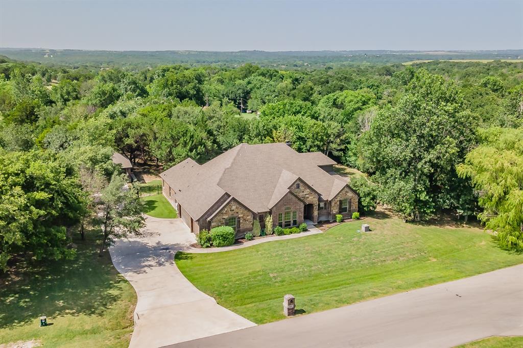 It’s hard to find a home where the space actually matches the setting—but this one does. From the moment you walk in, the layout just works, with an open kitchen & living area that feels connected without being crowded, natural light drawing your attention toward the backyard, & a flow that makes everyday living easy. The kitchen sits right in the center with granite countertops, a large island, plenty of prep space, & a breakfast bar that keeps you part of the conversation, while the living room anchors the home with tall ceilings & a brick wood-burning fireplace. Downstairs, the primary suite is set apart for privacy along with three additional bedrooms. Upstairs offers two dedicated flex spaces—a media room & separate game room, both connected to a full bath—giving you flexibility for guests, a home office, fitness space, hobbies, or even a future 5th bedroom if your needs change. Step outside & you’ll immediately understand why this property feels different—a covered patio opens to a large stamped & stained concrete entertaining area, mature trees, a built-in stone fire pit, & more than an acre of usable space that’s getting harder to find in this area. Add in the 5-car garage setup, including a detached 2-car garage ideal for a shop, storage, or hobbies, plus well & septic, & a water softening system already in place, & you’ll quickly see this is a home built for the way people actually live today. Enjoy the feeling of country living with the convenience of Fort Worth nearby, all in sought-after Azle ISD & just minutes from Hwy 199, Lake Worth, & Eagle Mountain Lake.