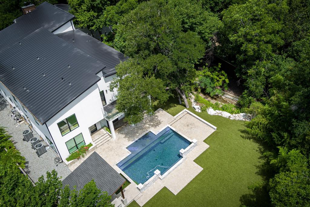 Luxury and comfort blend effortlessly in this exceptional open-concept home at 13032 Copenhill Road, situated in one of Dallas’ most desirable neighborhoods. With 6 spacious bedrooms, multiple living areas, a cozy loft, and a dedicated media room, this expansive residence is thoughtfully designed to accommodate both everyday living and upscale entertaining. Step inside to discover low maintenance flooring and custom light fixtures throughout, adding style and warmth to every space. The heart of the home is the chef-inspired kitchen, featuring stainless steel appliances, a large center island, and seamless flow into the dining and living areas—perfect for gathering with family or hosting guests in style. A wine cellar tucked beneath the stairs adds a unique and elegant touch. Outdoor living is just as impressive. Enjoy your private resort-style backyard complete with a sparkling pool and spa, custom putting green, and a meandering stream that adds serenity to the beautifully landscaped surroundings. Low-maintenance turf in both front and back yards ensures year-round curb appeal, while a tall privacy fence provides peace and seclusion. Multiple balconies and deck areas offer a variety of spots to relax, entertain, or simply enjoy the outdoors. A detached 3-car garage provides ample parking and storage, completing the home’s long list of desirable features. 13032 Copenhill Road is more than just a home—it’s a lifestyle destination. From its flexible layout to its luxurious finishes and thoughtfully designed outdoor spaces, this property offers the perfect blend of timeless elegance and modern convenience. Don’t miss your chance to own this rare Dallas gem.