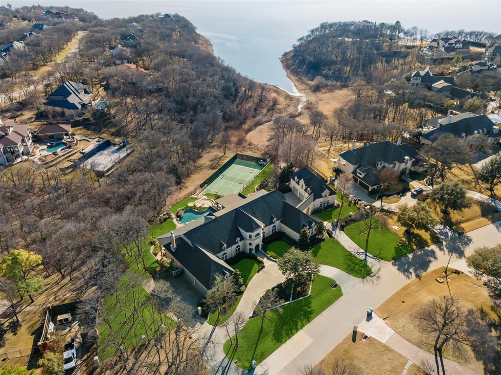 Waterfront property situated in the secluded, Guard Gated Point Noble! Nestled on 1.58 ACRES! 10,444 SF of luxurious living space including 1,009 apartment w-den, kit & balcony. 4 bedroom suites + casita. 7 full & 3 half baths + 7 car gar. Chef's Kit, Study, Exercise Rm w-rubber floor & WI sauna, Theatre, wine cellar, 4 FP, Game w-wet bar, multiple living & dining areas, 4th floor den w-wet bar + balcony. 3 Level water garden! Upgraded security system, extensive storage + sound system throughout! 7AC units. Huge 2nd floor balcony offers an indoor-outdoor lifestyle for lounging & panoramic Lake Grapevine views! Backyard masterpiece w-tennis courts, infinity pool & expansive lawns complete this impeccable estate.