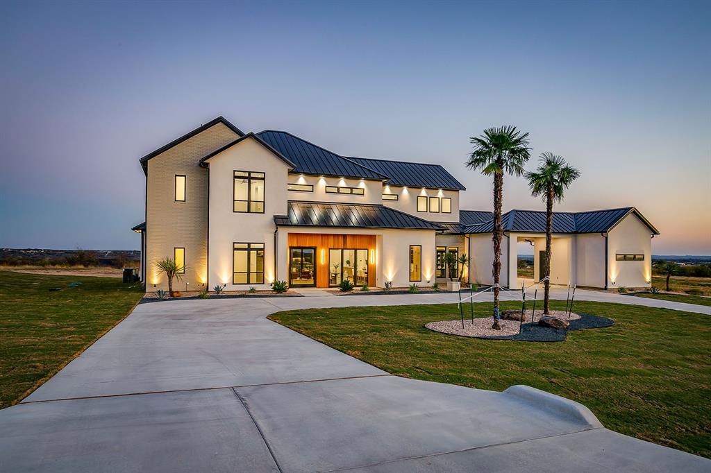 **NEW $40,000 BUILDERS INCENTIVE GOOD THROUGH JULY 1ST!** PREPARE TO BE CAPTIVATED! This high class architectural standout is the definition of bold, refined luxury and exceptional sophistication! Nestled in the sought-after Santorini gated community, you will find this one-of-a-kind home ready to dominate the first impression. As you drive through the Porte-Cochere–style design and half circle driveway, you will walk through a striking 6×8 metal and glass pivot door. Instantly welcome by a warm stone accent wall which opens to an airy, open-concept layout where a glass staircase ascends to a loft overlooking the living area. What a spectacular living room here with floor to ceiling Venetian-plastered fireplace and 24 foot ceilings with a full custom bar with additional sink and accent stone wall. The slated design kitchen is equipped with Taj Mahal countertops with a dropped edge finish, top of the line built-in SKS appliances, custom cabinetry including spice rack and utensils drawers, pot filler above gas cooktop, under cabinet lighting and an unbelievable pantry with custom wine bar. The dreamy primary suite offers an unbelievable cascading waterfall shower in what feels like a five-star resort style spa with 12 foot seamless glass walls. Each bedroom offers its own ensuite bath and impressively spacious closets, while the upper level features a flexible living space and a game room equipped with its own bar—perfect for entertaining. Home office with built-in's and laundry room with dog wash.  Enjoy beautiful wide-open views off the back patio with a glass of wine and cozy up to the wood-burning fireplace. This truly is a stunning design, packed with every luxury feature and is ready for YOU to call this place home for good!