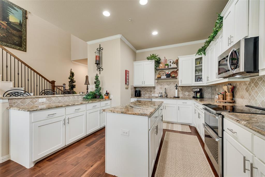 Meticulously maintained and move-in ready, this beautifully designed townhome offers a rare opportunity in Burleson, where townhomes are hard to find & even harder to match in quality. Designed for easy lock-and-leave living, this home combines low-maintenance convenience with upscale finishes throughout. Step inside to a grand entry featuring a stunning staircase with hardwood railing & decorative iron spindles. Rich hardwood floors flow throughout the downstairs living, dining, & kitchen areas, complemented by crown molding and an open, inviting layout. The spacious kitchen is a standout, offering abundant cabinetry, a large island, pantry, granite countertops, white shaker-style cabinets with brushed nickel hardware, tile backsplash, stainless steel appliances, and a double oven. It opens seamlessly to the oversized dining and living areas, creating the perfect space for entertaining. A sliding glass door with custom plantation shutters leads to a covered patio and a surprisingly generous backyard with landscaping, an uncommon feature for townhome living. Upstairs, all three bedrooms are efficiently laid out, along with a beautifully decorated hall bath featuring decorative tile, granite countertops, and an upgraded mirror. The primary suite is spacious and private, complete with a walk-in closet, balcony, and plantation shutters. The ensuite bath offers dual sinks, granite countertops, a separate soaking tub and shower, elegant tile work, and a large linen closet. A convenient upstairs utility room includes cabinetry and a built-in ironing board. Additional features include spray foam insulation for energy efficiency & a private 2-car garage.  The HOA covers exterior maintenance, lawn care, trash service, and roof & exterior insurance. The gated community also features iron fencing and park areas.  Located in Burleson ISD with easy access to shopping, lots of restaurants, and only a 7 minute drive to HEB! This home offers a luxury feel at an exceptional value!