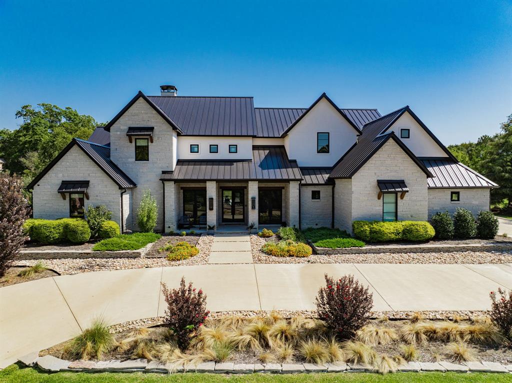 Welcome to your dream retreat—an exceptional modern luxury home built in 2020, perfectly situated on a spacious 1.467-acre lot directly across from the serene waters of Lake Ray Hubbard! This stunning 5 bedroom, 5 bathroom estate offers 5,002 sqft of living space, 7,157 sqft total under roof and is designed for both upscale living and effortless entertaining. Inside, clean lines and high-end finishes define the open-concept layout. The chef’s kitchen is a true showstopper, complete with a gas range, built-in refrigerator, double ovens, a drawer fridge, floor to ceiling wine rack, and ample custom cabinetry. Adjacent is a spacious living area flooded with natural light. You'll find a dedicated office featuring custom built-ins—perfect for working from home in style. The primary suite is a private oasis, boasting his-and-hers everything—double toilets, vanities, and sinks—along with generous walk-in closets. Each additional bedroom is spacious and thoughtfully laid out, offering comfort and privacy with its own ensuite bathroom. 4 bedrooms are located on the first floor along with the game room and office! Upstairs features another living area, the 5th bedroom and a bonus room with closet; perfect for a in-law suite set up to have own bedroom and living room. Step outside to your covered patio with outdoor kitchen overlooking a sparkling pool, putting green and expansive fenced backyard—ideal for relaxing, entertaining, or simply soaking in the peaceful atmosphere. A spacious 4-car garage and ample parking with a double wide driveway to provide plenty of room for vehicles and guest. For added convenience, this property is equipped with smart home features that control garages & lights with the touch of a button from your phone, as well as having a surround sound system installed inside, outside and around the pool! Luxury, comfort, and location all come together in this one-of-a-kind property. Don’t miss the opportunity to own this extraordinary home with lake views.