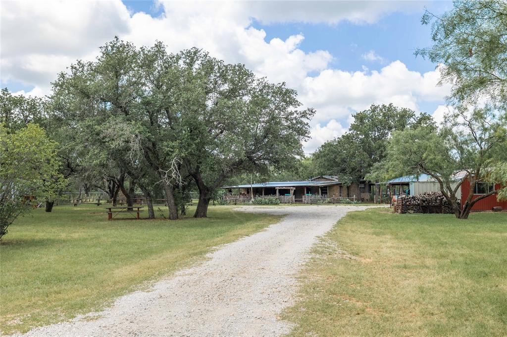 Motivated seller!!! This remarkable rustic rock home was built by a true Rocky Mountain craftsman, showcasing his skill and love for the land. Constructed from solid stone and rich cedar, it offers an authentic mountain cabin feel with the durability and warmth you’d expect from such thoughtful design. Tucked away on a secluded, scenic property midway between Brownwood and Lake Brownwood, this home offers a rare combination of privacy, natural beauty, and endless potential. From the moment you arrive, you’ll be captivated by the serene setting a heavily wooded haven with majestic, mature live oaks, post oaks, and red oaks that provide dappled shade and support a thriving wildlife population. Whitetail deer roam freely, and a stocked pond adds a peaceful, pastoral charm while inviting you to fish or simply relax by the water’s edge. This truly is some of the prettiest and most secluded land in Central Texas, ideal for anyone seeking a quiet retreat or a working homestead. In addition to the inviting main home, the property includes numerous features that make it as functional as it is beautiful: A detached garage provides convenient parking and ample storage for vehicles and equipment. An enclosed hobby room or craft area is perfect for creative projects, canning, or even a dedicated outdoor kitchen space for entertaining. A separate area of the property is designed for horses, show cattle, or other livestock, with two large barns. One barn is connected to well built pipe pens, ideal for training, sorting, or housing animals in individual pens making it easy to start or expand the animal operation you’ve always dreamed of. The land is fully fenced and thoughtfully laid out, offering plenty of room to roam, work, and play. Whether you envision a private wildlife sanctuary, a productive ranch, or simply a charming country getaway to enjoy with family and friends, this property is ready to make that vision a reality. Don’t miss this opportunity to own Texas treasure!