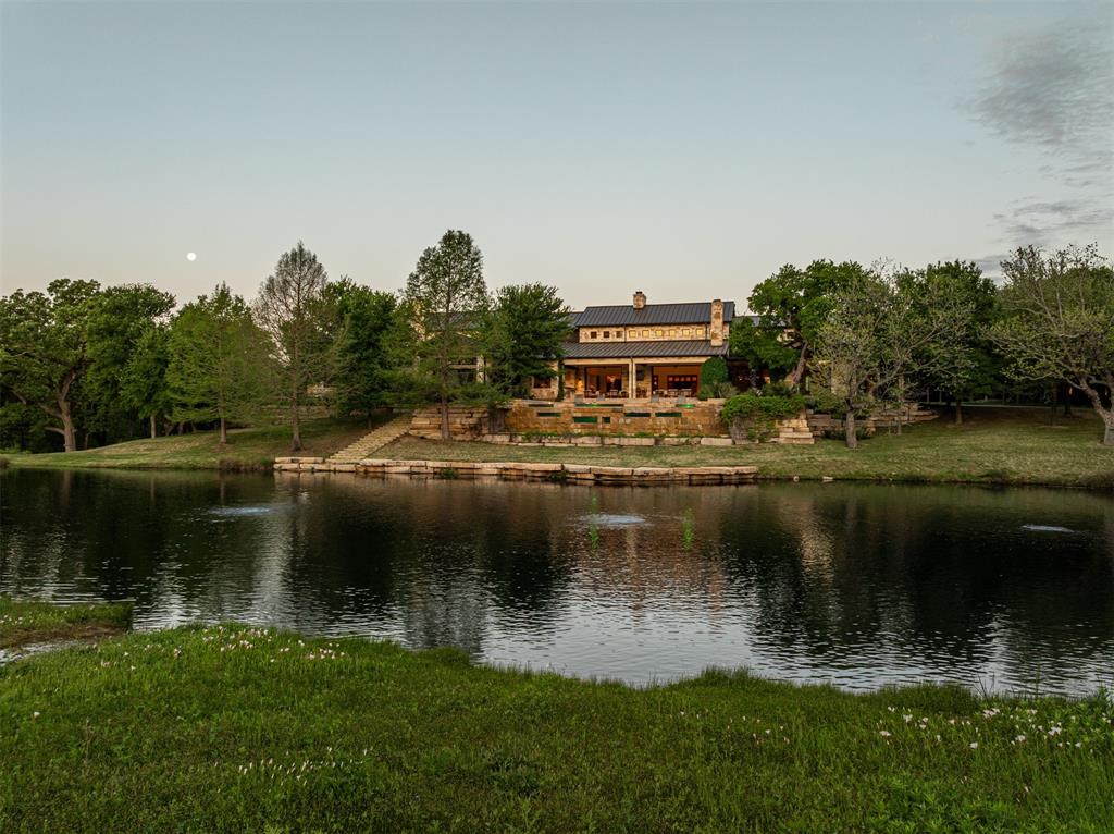 Tucked away in one of the Metroplex's best-kept secret neighborhoods, this extraordinary 6.729-acre gated estate offers a level of privacy, luxury, and natural beauty that is truly unrivaled. Formerly owned by David Fair, the previous structures were razed by the current owners and Sharif & Munir Custom Homes completed a one-of-a-kind Texas Hill Country-inspired retreat completed 2015 at no expense spared.

Anchored by a stunning one-level Austin-stone main residence with 12,335 square feet of living space under standing seam metal roof, the estate is perfectly positioned above a spring-fed creek and private one-acre lake stocked with bass and catfish. The land itself is a masterpiece: 30+ feet of elevation changes, native wildflower meadows, limestone outcroppings, and over 100 hand-selected trees curated by Southern Botanical and The Hocker Group. Sunken, lighted tennis court (2021), resort-style negative edge heated pool with underwater windows, and boathouse fishing dock add to outdoor lifestyle offerings.

The main home features soaring 20+ foot ceilings with expansive living areas that flow out to resort-worthy verandas with drop down screens. A gourmet kitchen and separate prep areas are outfitted with top-of-the-line appliances, while a 678-bottle wine cellar and bar-equipped game room offer unmatched entertainment value. The award-winning 20-seat home theater with an immersive 3D audio system designed by HomeTronics delivers a cinematic experience beyond comparison.

Other amenities include: 9-car, climate-controlled garages and workshop, two-bedroom attached guest house, geothermal HVAC, tornado shelter, lightning protection system, and irrigation drawn from 1,800 ft water well. 18,668 feet total under roof. The Collin and Denton county line bisects the estate which enables Plano Schools while the homesite enjoys the Denton CAD tax rate. This estate is ideal for executives, athletes, or those seeking unmatched serenity in this central location.