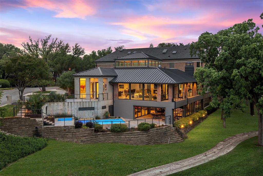 17214 Club Hill is a refined expression of modern luxury, thoughtfully reimagined and expanded in 2020 to nearly 8,964 square feet. Taken to the studs, the residence was rebuilt with all new systems—electrical, plumbing, HVAC, insulation, windows, and roof—and enhanced by integrated Control4 technology for seamless whole-home audio, video, lighting, and security. The interiors are expansive yet composed, defined by floor-to-ceiling Pella architectural windows and multi-slide doors that frame sweeping views across two fairways and White Rock Creek. Level 5 wall finishes, porcelain concrete flooring, custom wood ceiling panels, and stone feature walls create a layered architectural backdrop, while dual floating staircases with integrated lighting serve as sculptural focal points. Linear fireplaces, motorized Lutron shades, and curated lighting further elevate the atmosphere. The kitchen is both functional and beautifully appointed, featuring a large center island, Thermador appliance suite with gas range, double ovens, warming drawer, and dual dishwashers, along with a butler’s pantry and secondary refrigeration. Additional spaces include a wine and whiskey room, media room with 120” screen, game and billiards room, private office, guest suite, and generous laundry and storage. Outdoor living is intentionally layered, with a multilevel pool and spa, firepit, and terraced landscaping positioned to capture the home’s elevated vantage point. Motorized screens create seamless indoor-outdoor transitions, while a circular drive, detached three-car garage, and HOA-maintained grounds offer a true lock-and-leave lifestyle. Bent Tree is entering a new chapter with a 65,000-square-foot clubhouse and a course transformation by Beau Welling. Long recognized as a premier golf destination, the Desmond Muirhead-designed course is being thoughtfully reimagined, complemented by exceptional racquet facilities and a culture of excellence.