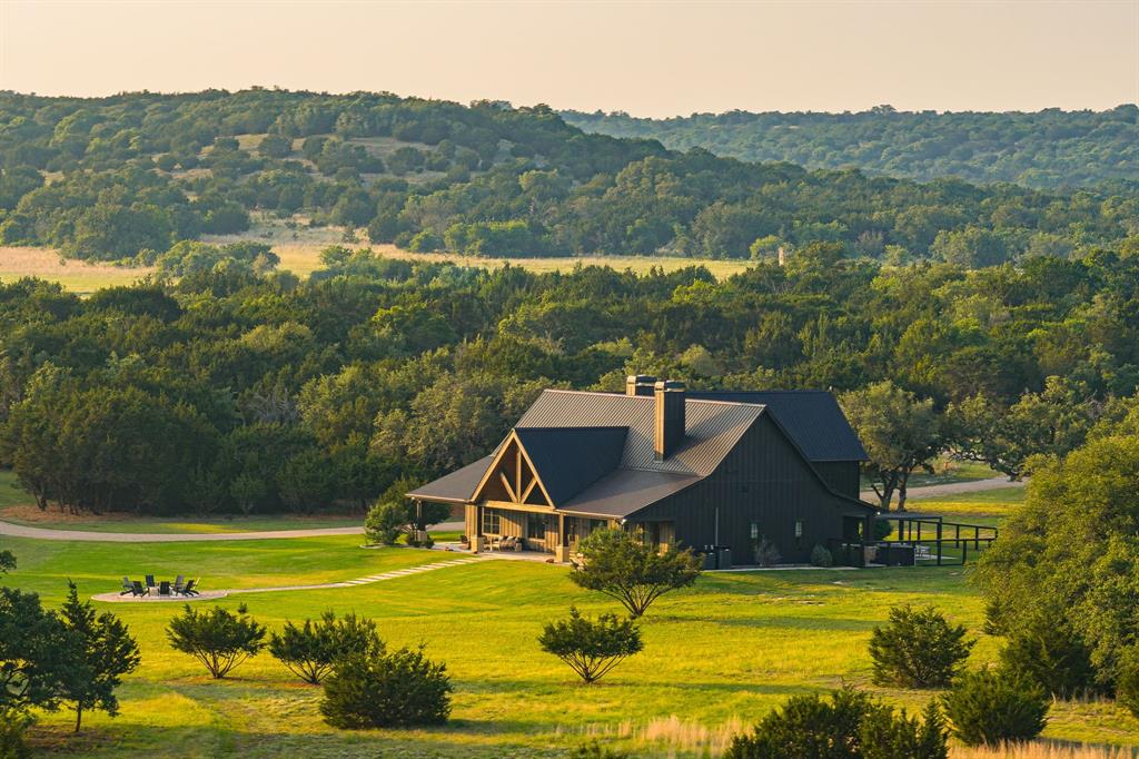 Oak Hill Ranch is a turnkey luxury ranch offering refined living, outstanding recreation, and panoramic views overlooking Cranfills Gap — all just 2 hours from Austin and DFW. The 4,300 sq ft custom home features 4 beds, 3.5 baths, and high-end finishes throughout — Grade A marble countertops, an Italian ILVE range, Venetian plaster accents, Marvin Elevate windows, two gas fireplaces, and Kallista fixtures. Outdoor living is equally impressive with covered patios, a pergola, Nordic hot tub, built-in Coyote grill, and a resort-style fire pit. The land features rolling topography, mature hardwoods, native pastureland, and scenic elevation changes. Wildlife is abundant — whitetail, Rio Grande turkey, dove, and more — with an active Wildlife Management exemption in place. A custom 2-acre golf practice range with two tee boxes and eight wedge targets adds a standout recreational feature. The perimeter is fully fenced with well-maintained interior roads throughout. Infrastructure is built for self-sufficiency: a dedicated well with 1,000-gallon storage, 500-gallon propane, a 150-ft internet and cell booster tower, high-speed Pathway Internet, and dual 550-gallon fuel tanks. Included equipment: Kioti DL4510 tractor, 2021 Polaris Ranger 1000, and a John Deere zero-turn mower.