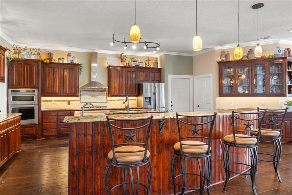 Experience the charm of Texas living with this stunning, rustic style home with many features only found in custom homes. This one of kind property is a peaceful escape or perfect for daily living, offering a combination of comfort, function, elegance, and natural beauty. Step inside to discover a spacious open-concept layout featuring a grand living room boasting a beautiful stone fireplace with a wall of windows overlooking the back of the property. Spacious chef's kitchen with abundant counters and cabinetry, 2 sinks and Kitchen Aid appliances make for a gathering place to entertain. Plenty of room to seat your guests in the dining room, the kitchen island, and breakfast nook. The primary suite is a true retreat with a fireplace separating the main sleeping area and an office-den room overlooking the back of the property. The bonus room is located upstairs off the primary suite. Spacious with built in desks, storage, and a full shower bath make it perfect for a game room, library, man cave, quiet retreat, homeschool area. Three inviting bedrooms with baths make for privacy with family & guests on the other side of the house. A 4th room is flexible & can be used as additional bedroom or office with half bath. The laundry-utility room has abundant storage, sink, and dog wash station.  Lower level offers a 4 car garage & other space currently used as a workout room, woodworking shop,& storage. A walk out at the lower lever is covered to relax, enjoy nature while the upper level offers a composite deck for a spectacular view. The 2 acre lot is partially fenced and offers access to the river with a natural pathway. 
Pecan Plantation is a gated community with many amenities to enjoy.  Golf courses, clubhouse, restaurants, shopping center, hardware store, bank, pharmacy, salon, parks, pickleball, tennis, marina, & more so you never have to leave.  Historic Granbury square is a short drive to enjoy entertainment, dining out,& shopping.