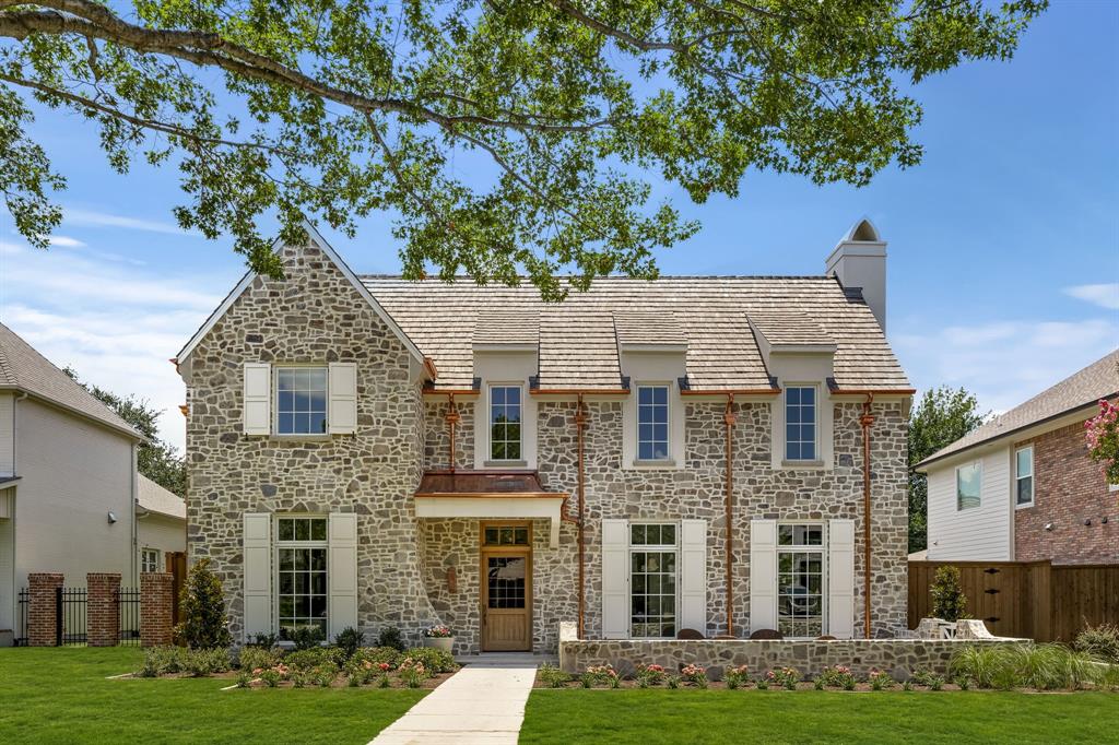 6526 Woodland Drive is a new construction residence by Mosaic Building Co. with McLean Interiors and Briggs Architecture & Design, blending timeless materials with modern functionality in the heart of Preston Hollow. A striking natural stone exterior, synthetic cedar shake roof with copper accents, limestone porch cladding, and a custom white oak entry door with leaded glass establish understated elegance. Inside, white oak wide-plank hardwood flooring and millwork, lime-washed living room walls and ceiling, and custom iron stair railings create a warm, architectural palette. Designed for everyday living and entertaining, the main level offers exceptional sightlines between the dining room, kitchen, living room, and lounge, while floor-to-ceiling windows fill the home with natural light. The secluded downstairs primary suite features vaulted ceilings and a spa-inspired bath with heated natural stone floors, marble finishes, a standing shower, and freestanding soaking tub. Four additional upstairs bedrooms each include ensuite baths and walk-in closets, along with a spacious game room and second laundry room.The kitchen combines craftsmanship with professional-grade performance, featuring a 48-inch Wolf range, custom brass hood, marble countertops, a butler’s pantry, walk-in pantry, built-in breakfast banquette, expansive island, and paneled appliances. Soft-close inset cabinetry and white oak detailing continue throughout. Outdoor living includes motorized patio shades, recessed heaters, a built-in grill with refrigerator, masonry fireplace, wood storage, and gas connection for a future courtyard fire feature. Additional highlights include Lutron lighting controls, trimless recessed lighting, AV prewire, two-stage Lennox HVAC, two Navien tankless water heaters, decked attic storage, and an oversized rear-entry garage with epoxy flooring and an automatic sliding gate. Every detail reflects enduring materials, thoughtful craftsmanship, and livable luxury