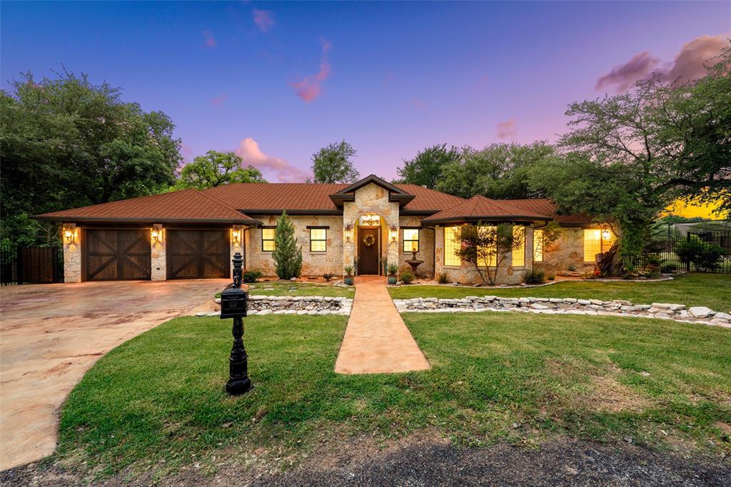 Tucked away on a beautifully treed 1.5 acre setting, this custom stone home sits on not 1, but 2 full lots, offering space & privacy that is hard to find. Built with intention, every detail was thoughtfully curated to create a seamless blend of comfort & elevated living. From the moment you arrive, the circular drive & mature trees set the tone for a peaceful, secluded setting. Inside, the home features a spacious, functional layout with an open concept design, 2 separate living areas, & wide hallways. The kitchen is centrally located & connects effortlessly to the main living & dining spaces, making it ideal for everyday living & entertaining. Large windows throughout bring in natural light & showcase beautiful views from nearly every room. Custom elements truly set this home apart, including handcrafted doors, a heavy custom chandelier, & thoughtfully selected finishes throughout. Beautiful drapery with custom rods & custom made blinds add another layer of detail, while abundant storage & oversized closets provide both style & function. The primary suite is privately situated & offers a spacious retreat with a large ensuite bathroom, separate toilet room, & generous closet space. Additional bedrooms are positioned on the opposite side of the home, offering privacy & flexibility. A dedicated laundry room, oversized storage areas, & a large garage add to the home’s functionality. Step outside & the property continues to impress. A large covered patio with wood ceilings, stone columns, & multiple seating areas creates the perfect space for entertaining or relaxing. Just beyond, a dedicated fire pit area & expansive backyard filled with mature trees create a true private park setting. The outdoor space is equally thoughtful, featuring custom gates, a durable steel post fence, & a batting cage. With 2 full lots totaling 1.5 acres, curated design, & quality craftsmanship throughout, this property offers a rare combination of luxury, privacy, & everyday livability.