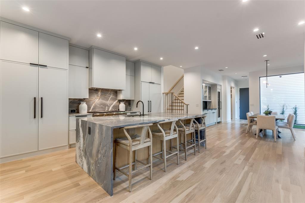 Perfectly situated across from the iconic Highland Park Fountain on a quiet, low-traffic street, this stunning three-level home blends sophisticated design with effortless urban living. This residence is thoughtfully designed to deliver both style and functionality. Step inside to a light-filled interior where soaring ceilings and expansive windows highlight the sleek, contemporary finishes. The gourmet kitchen is a chef’s dream, featuring premium appliances, custom cabinetry, and an oversized marble island ideal for entertaining or casual dining. The open-concept living and dining areas create a seamless flow, making this home perfect for gatherings both large and small. This residence is fully tech-enabled, featuring in-ceiling speakers, Wi-Fi extenders, HD big-screen TVs, a private circuit security camera system, and electronic shades throughout , all designed for modern convenience and peace of mind. The second-floor primary suite serves as a serene retreat, boasting a luxurious spa-like bathroom with high-end fixtures, a soaking tub, and generous closet space. Two additional bedrooms, each with en suite bathrooms, provide comfort and privacy for family or guests. Outdoor living is a true highlight, with a private ground-level patio and a partially covered rooftop deck with an electronically controlled roof that opens and closes, perfect for quiet nights under the stars or entertaining with panoramic views. With unmatched walkability to the Shops at Highland Park and nearby dining and entertainment, this home offers the best of Dallas living in one of the city’s most desirable neighborhoods. This property is a rare opportunity to enjoy upscale finishes, cutting-edge smart home technology, a prime location, and exceptional design.
