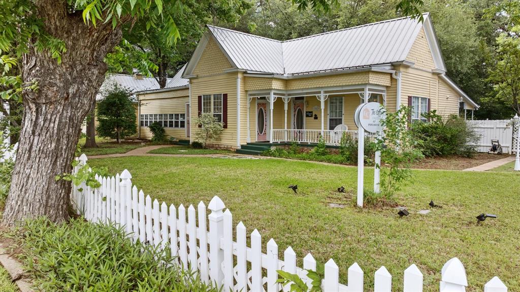 Welcome to The Pomegranate House and Cottage Collection, one of Granbury’s most iconic and distinctive investment opportunities. The Pomegranate House, formerly known as the Ratliff House, was built in 1906 and is an exceptionally well-preserved example of Victorian Eastlake architecture. Located just 0.7 miles from the Historic Granbury Square and minutes from Lake Granbury, this beautifully preserved historic property blends timeless charm, architectural character, and income potential. The main home features double primary bedrooms, each with its own ensuite bath, two living areas, a dining room, kitchen, utility-laundry room, and a welcoming covered back porch overlooking a serene courtyard. Surrounding the courtyard are four charming cottages, each thoughtfully designed with a private bedroom and ensuite bath to provide guests with comfort and privacy. Currently operating as a successful income-producing short-term rental, the property offers six total bedrooms across the main home and cottages. A separate on-site lounge with a fully stocked coffee bar and arcade games enhances the guests' experience. The property also includes a dedicated laundry cottage equipped with multiple washers and dryers, as well as two additional storage and supply rooms to support operations.  The beautifully landscaped grounds are anchored by majestic Live Oak trees estimated to be 300–400 years old, as verified by the Hood County Master Gardeners. They are living testaments to the property’s enduring legacy.  A peaceful pond with waterfall, inviting outdoor gathering areas, and exceptional curb appeal complete this truly remarkable setting.  Situated on a fully fenced 0.519-acre corner lot, the property is offered fully furnished and fully equipped for a true turnkey opportunity. Endless possibilities await, continued short-term rental use, ideal for family gatherings, boutique hospitality, event venue, office space, or bed and breakfast. Property tour video available upon request.