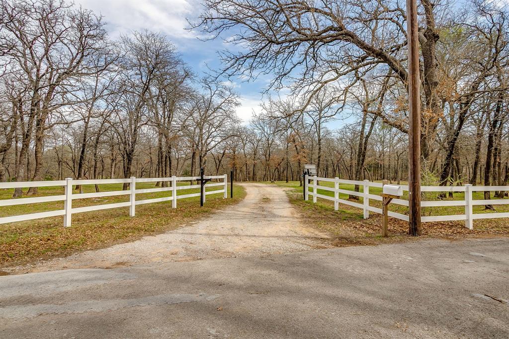 Nestled on 18 scenic acres and accessed through two private gates, this thoughtfully improved property offers both privacy and natural beauty. The home sits slightly elevated, allowing you to take in sweeping views from both the front and back porches. The spacious back porch is designed for relaxation and entertaining, featuring an outdoor kitchen, hot tub, and views overlooking a tranquil saltwater pool. Beyond the home, the back pasture includes a tank and several feeders, and the property has attracted an impressive variety of wildlife over the years. The land is well-equipped for country living and agricultural use. Improvements include a 30×40 metal shop, livestock barn, chicken coop, and silo—all with electricity. Seven exterior hose bibs are installed throughout the property for convenient water access. A large fenced garden area and multiple outbuildings add functionality, while extensive fencing, including double-fenced sections, supports livestock management. Goats currently on the property maintain the agricultural exemption and will convey with the sale. The home offers approximately 2,100 square feet of living space with three bedrooms and two bathrooms. A cathedral ceiling with exposed wood beams highlights the main living area, creating a warm and inviting atmosphere. The eat-in kitchen is well appointed with a double island, prep sink, farmhouse sink, and pot filler. Just off the kitchen is an additional pantry that can serve as extra storage or a flexible workspace. The primary suite, features a recessed ceiling with mood lighting and exterior access to the patio. The primary bathroom offers a separate jacuzzi tub and dual shower system with a large walk-in closet. Additional amenities include a three-car carport, an oversized three-car garage, and ample parking throughout the property. This well-maintained estate combines comfort, functionality, and the charm of peaceful country living and truly has it all!