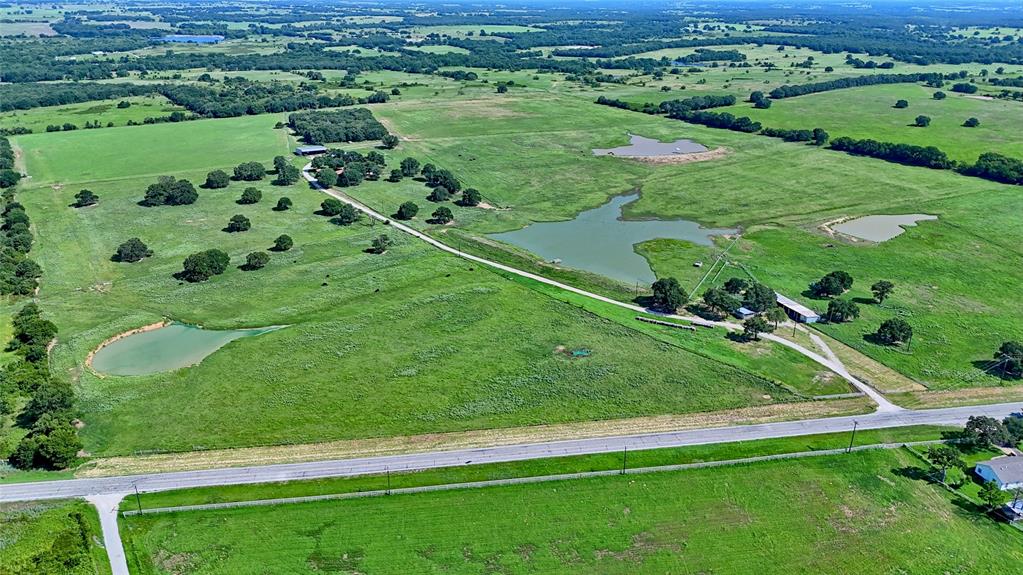 116 Acres of Texas Beauty and Opportunity! This incredible 116 acre property with scattered oak trees and Fm 1749 frontage offers the perfect blend of natural charm and agricultural functionality. Along with a move-in ready home with panoramic views, this is a haven for ranchers and dreamers. This well-designed property boasts expansive acreage covered in lush coastal grass, ideal for grazing and hay production. The land is thoughtfully cross-fenced and features a fully operational set of corals, streamlining livestock management and rotational grazing. With 2 water wells, including one conveniently located near the corrals and 4 large ponds, your cattle will always have access to a reliable water source. Property also includes a large, impressive, insulated shop with roll-up doors, separate office space and outdoor coverage perfect for storage or workspace. Additionally, there are 3 electric meters, a barn, and a large covered parking area for tractors and equipment. This exceptional find also has a sprawling 2,264 sq ft, 3 bed 2.5 bath home positioned to take advantage of the gorgeous views. The home has an open floor plan and split-bedroom layout offering ample space and opportunities for the entire family. The kitchen with granite counter tops and double oven is open to the main living area and has a pass-through opening into the large flex space with an additional fireplace. Whether you are looking to expand your herd with this ready-to-go operation or settle into peaceful country living with room to grow, a property with acreage of this Quality is a rare find. Property is currently ag exempt.