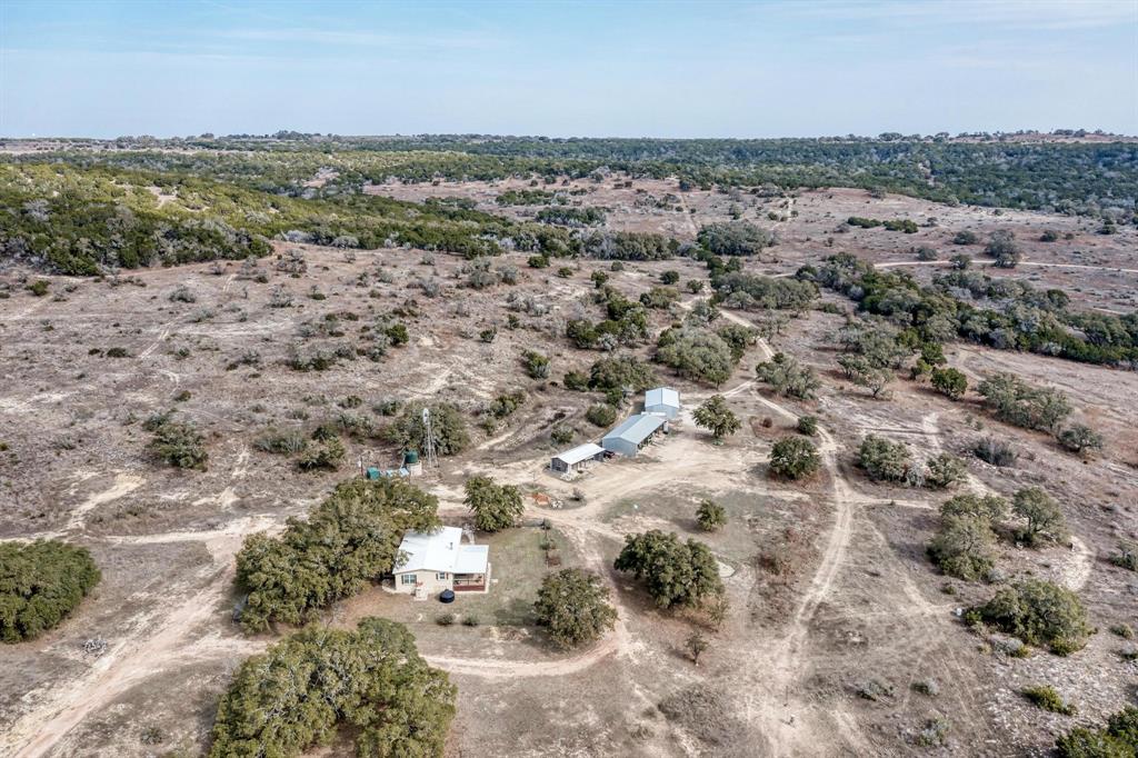 Presenting a premier Texas Hill Country ranch, this 201-acre estate in the revered Pedernales Canyon Lands offers a distinguished opportunity for recreation, corporate retreats, or an impressive private homestead. Its exceptional position guarantees an enduring sense of solitude—a rare commodity in today's evolving landscape. For over thirty years, this property has been the beneficiary of conscientious, holistic management. The topography unfolds in graceful, rolling hills blanketed by native grasses and a generous array of indigenous hardwoods, notably featuring magnificent specimens of White Oak, Spanish Oak, Chinquapin, and ancient Pecans. Throughout the expansive grounds, large heritage oak trees stand as sentinels, providing critical habitat for a flourishing population of white-tailed deer, hogs, and turkey. Substantial water resources, including a deep seasonal swimming hole and various ponds, are complemented by the security of two established wells fed by the Major Trinity Aquifer. From elevated positions reaching 200 feet, the views are nothing short of breathtaking, offering a profound sense of peace. A delightful 3-bedroom, 2-bathroom residence, perfectly nestled amidst a grouping of heritage oaks and adorned with the striking colors of pride of Barbados and yellow bells, provides an inviting dwelling suitable for primary residency, a tranquil escape, or elegant guest facilities. Supplementary covered storage ensures ample space for equipment, animal provisions, or recreational vehicles. With a convenient drive of approximately 30 minutes to Liberty Hill and 1 hour 15 minutes to Austin, this ranch masterfully balances serene isolation with desirable connectivity. For those whose desire is long-term privacy and an escape from encroaching development, this property warrants serious consideration!