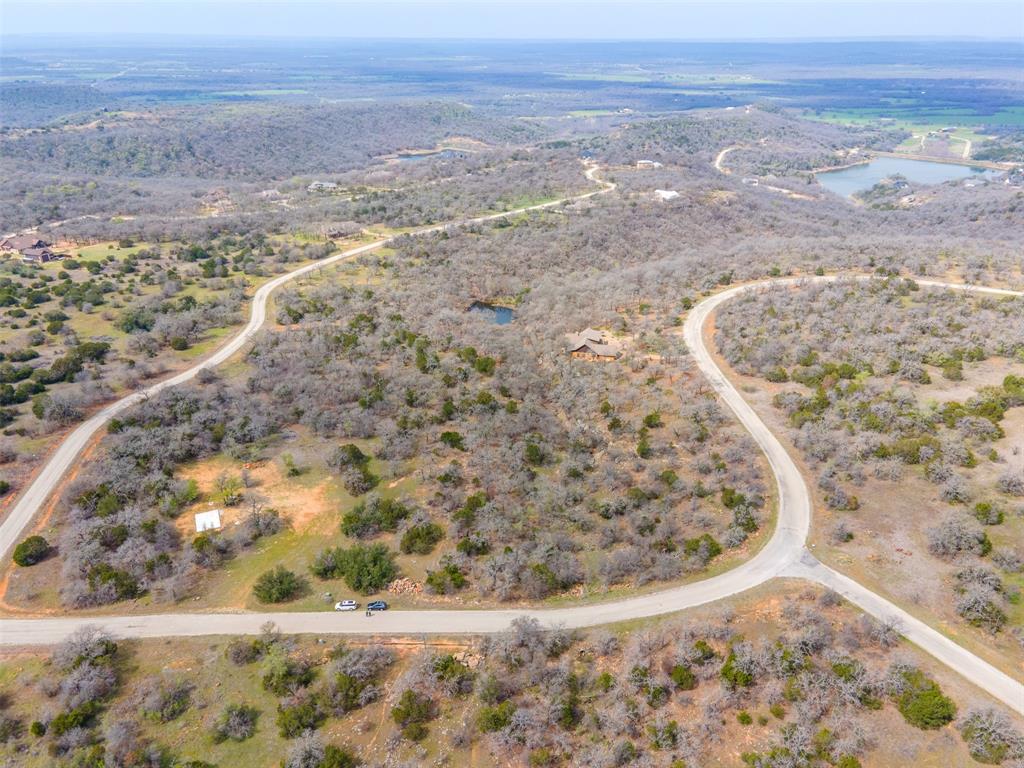 Build Your Dream Home on 2.87 Acres in The Ranches at Clayton Mountain, Gordon TX. Rare 2.87 acre corner lot in The Ranches at Clayton Mountain, a premier gated resort community just 60 minutes from Fort Worth and 90 minutes from Abilene, near Palo Pinto Lake and Possum Kingdom Lake. This large corner lot features a flat area ideal for building your dream home, a scenic gully with a small stream, abundant wildlife, and striking rock outcroppings for a true Hill Country feel. Enjoy resort style living with walking access to Sundance Club, the community hub offering two pools, cabanas, a restaurant, and pickleball courts. Just around the bend, the Ruff Center features a 12,000-square-foot fitness facility, steam room, hot tub, game tables, movie theater, resort pool, sand volleyball, and playground. The Cove at Lake McIntire includes a clubhouse, pool, fishing pier, boats, and kitchen for residents. Additional amenities include nature trails at Eagle’s Nest, weekend hotel style rooms available to club members, and organized community events that foster a close-knit neighborhood atmosphere. Whether you’re seeking a full-time residence, weekend retreat, or vacation home, this Gordon TX gated community lot provides the perfect combination of privacy, natural beauty, and resort-style amenities. Build your custom Hill Country home in a location that combines scenic tranquility with easy access to Fort Worth, Abilene, and nearby lakes. The lot’s corner position, mature trees, and versatile terrain offer unmatched flexibility for your dream home design, landscaping, and outdoor living spaces.