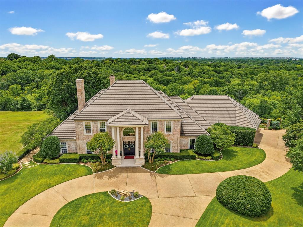 Enjoy resort-style living in this exceptional private retreat in the prestigious guard-gated golf course community of Mira Vista. Situated on a rare .67-acre lot adjacent to tranquil parkland, this elegant 4-bedroom, 4.5-bath home offers sophisticated living with thoughtfully designed spaces for both entertaining and everyday comfort. The chef’s kitchen is equipped with premium appliances, double ovens, an oversized Sub-Zero refrigerator, custom cabinetry, and generous workspace, while the expansive primary suite features a private exercise room, sauna, and spa-inspired bath. A secondary ensuite bedroom and spacious office that can serve as a fifth bedroom complete the main level. Upstairs, two additional ensuite guest rooms and a game room with wet bar and balcony showcase spectacular views. Outside, a sparkling pool and spa, built-in grill, retractable screen, and inviting outdoor living spaces create a true backyard oasis. Complete with a full-home generator and abundant storage, this remarkable residence offers luxury, privacy, and security in one of Fort Worth’s most sought-after neighborhoods.