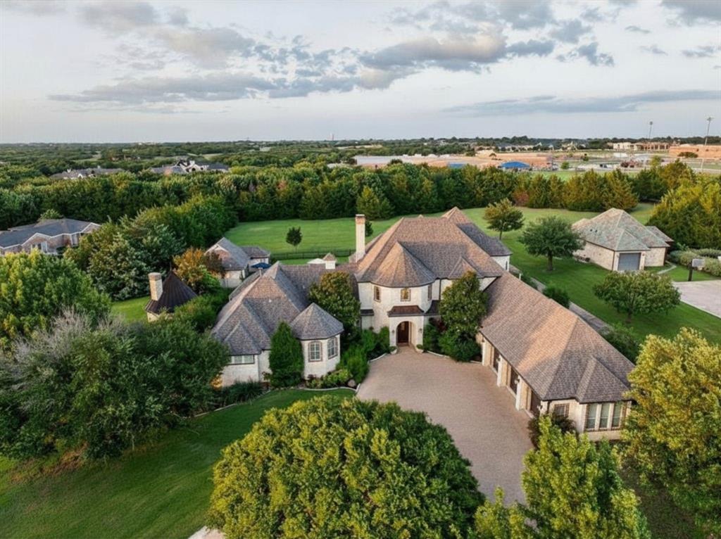 In the Hills of Buffalo Creek, this nearly two-acre estate offers a lifestyle that is increasingly rare: the ability to enjoy vast, private grounds while remaining within 30 minutes of the Dallas metroplex. With 6,558 total sqft of living area between the main house and the detached casita, it is a home designed for those who value updated, grand spaces for entertaining but want every room to feel cozy, intentional, and warm.

Expansive windows fill the home with natural light, highlighting white oak hardwoods and Austin stone throughout. The main residence features multiple living areas, a first-floor guest suite, media room, temperature-controlled wine room, built-in bar, and a chef’s kitchen that serves as the heart of the home. Upstairs, three additional bedrooms are complemented by a private living area with balcony access.

The primary suite serves as a private wellness retreat with a fireplace, spa-inspired bath, coffee bar, and dedicated exercise room. The detached 652 sqft casita includes its own kitchen and full bath, making it ideal as a guest house, pool house, or executive home office.

Backing to a permanent tree-lined greenbelt, the grounds feature native landscaping, a heated saltwater pool and spa, fireplace pavilion, and five-car garage capacity, including a climate-controlled two-car space. Located minutes from Lake Ray Hubbard and within Rockwall ISD’s highly regarded schools.
