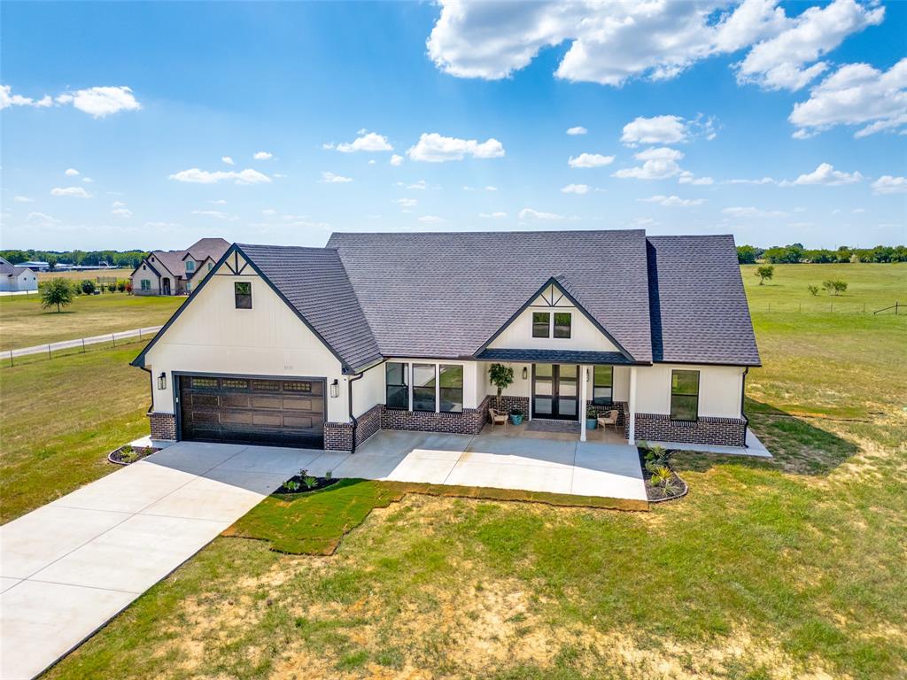 Modern farmhouse-style home on 1.79 acres with bright open living spaces, thoughtful design, and a beautiful country setting. The inviting exterior features a covered front entry, wide driveway, and clean curb appeal. Inside, the open-concept layout connects the living, dining, and kitchen areas with abundant natural light, neutral finishes, and a warm, polished feel throughout. The kitchen is a standout with quartz countertops, white cabinetry, stainless steel appliances, a farmhouse sink, large center island, sleek hardware, pendant lighting, and upper cabinets with glass-front accents and lighting. A dedicated office or study provides a flexible space for work, hobbies, or quiet retreat. The primary suite is thoughtfully separated from the secondary bedrooms and features a spacious bedroom, updated bath with dual sinks, large walk-in shower, and impressive custom closet with built-ins. Outdoor living continues on the covered patio overlooking open surroundings. A beautiful blend of modern design, comfort, and country charm in Ennis.