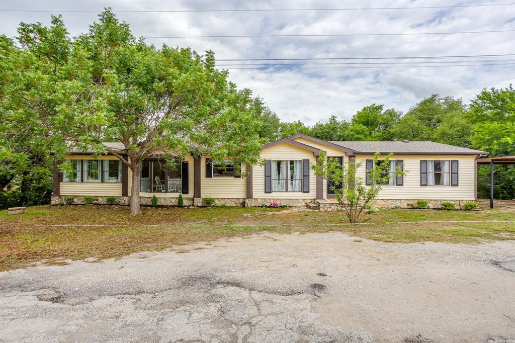 Set in a gated community with access to Lake Granbury, this home offers a layout that feels both inviting and easy to live in day to day. From the moment you walk in, you’ll notice the updated paint, flooring, and fixtures that carry throughout the home, giving it a clean, cohesive feel. The kitchen is set up to be both functional and a natural gathering spot, featuring an island with range, open accent shelving, granite countertops, and SS appliances. The space flows comfortably into the living area where a built-in entertainment center anchors the room and sliding glass doors open to the back deck. A second living room gives you extra flexibility, surrounded by windows and a wood-burning fireplace that makes it feel warm and cozy, especially in the evenings. Both dining areas feature oversized windows that bring in an incredible amount of natural light, so the whole home stays bright and connected to the outdoors. There’s a separate laundry room, which makes everyday life a little more convenient. The primary suite is where this home really shines, spacious enough for a sitting area, with a walk-in closet and an ensuite bath that feels more like a retreat. You’ve got a custom tiled walk in shower, a freestanding soaking tub, linen storage, and separate vanities with updated granite. And the windows bring in so much light, it feels so open and calm. Out back, the large deck is the kind of spot you’ll actually use—perfect for sitting with a drink, watching the birds, and slowing things down a bit. There’s a small fenced area ready for your garden, pets, or a Pinterest project space. The carport provides covered parking, and mature shade trees round out the setting. Living here means you get to enjoy the community amenities, including two pools, two boat ramps, a park, playground, and both tennis and basketball courts. It’s a great setup if you want to be close to the water and still have plenty to do right there in the neighborhood.