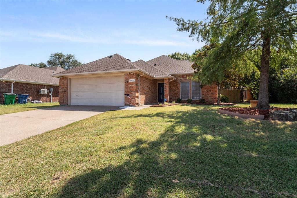 Move-in ready 3-bedroom, 2-bath home in Waxahachie offering thoughtful updates and classic curb appeal. Gleaming wood floors flow throughout the home—no carpet—creating a warm, low-maintenance living space. The expansive primary suite includes a generous closet and a beautifully remodeled bath featuring an impressive tiled walk-in shower. The heart of the home is a large kitchen with abundant storage, a roomy island for meal prep and casual dining, cook on gas range and cooktop and an open sightline to the living area anchored by a cozy gas fireplace. Step outside to a covered back porch perfect for relaxing or entertaining, a well-kept yard shaded by mature trees, and a fairly new storage building for extra convenience. Clean, comfortable, and ready for immediate move-in.