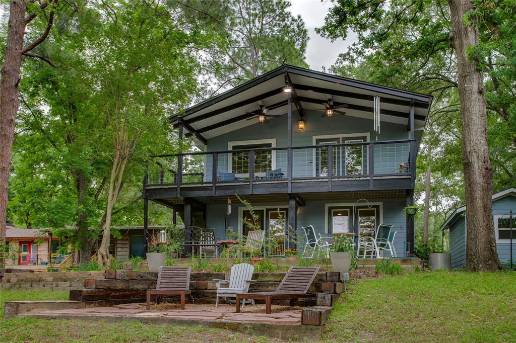 Beautifully tucked beneath mature trees on a lushly landscaped .54-acre lot in a protected cove, this thoughtfully reimagined lake house feels like the ultimate escape from city living. Equal parts cozy cabin retreat and elevated lakeside getaway, the home offers tranquil waterfront views, abundant privacy, and a true lock-and-leave lifestyle. Improvements include all new electrical, plumbing, tankless hwh, and more! Inside, natural light glimmers throughout the space, filtering through greenery and reflecting off warm finishes that make the home feel both airy and inviting. The first floor features two generously sized bedrooms, a full bath, laundry room, and ample storage—designed with comfort and functionality in mind. Upstairs, vaulted ceilings with exposed wood beams create a warm, relaxed atmosphere in the open-concept living space. Ideal for entertaining, the second floor seamlessly blends living, dining, and kitchen areas while framing peaceful views of the water and surrounding trees. The updated kitchen is equal parts stylish and functional, thoughtfully designed for gathering with ease. Lovingly updated, the home features an impressive list of improvements including updated windows, new flooring throughout, renovated kitchen and baths, a widened staircase, all new exterior siding, fresh interior and exterior paint, updated landscaping, new flatwork and concrete walkways, tankless water heater, HVAC, plumbing, electrical, and much more. Outside, the expansive lot continues to impress with a covered balcony, covered patio, boathouse, workshop with electricity, two-car carport, mature trees, and beautifully maintained grounds that invite long weekends spent outdoors. Located in Loon Bay, residents enjoy access to two neighborhood parks and a boat launch, while Cedar Creek’s shops, restaurants, and lake amenities are just moments away. Relaxed, refined, and designed for easy lakeside living—186 Harbor Drive is the kind of place you’ll never want to leave.