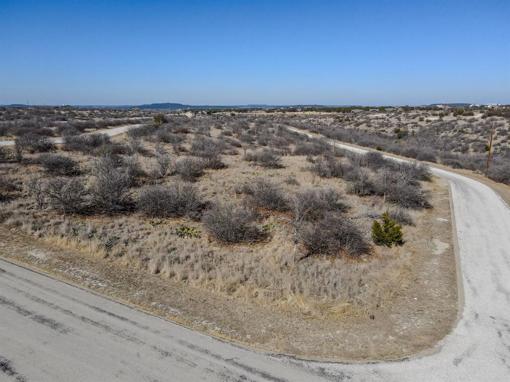 Build your custom home on this .305-acre corner lot in The Cliffs Resort at Possum Kingdom Lake. Situated within one of PK’s most prestigious gated communities featuring a 24-7 guarded entrance, this homesite offers an exceptional blend of privacy, security, and resort living. Ownership includes 36 complimentary rounds of golf annually along with access to upscale amenities such as a private marina with boat ramp and community dock, resort-style pool, fitness center, clubhouse, on-site restaurant, and tennis courts. Surrounded by scenic landscapes, parks, and walking areas, this property is ideal for those seeking a refined full-time residence or an elegant weekend escape at Possum Kingdom Lake.
