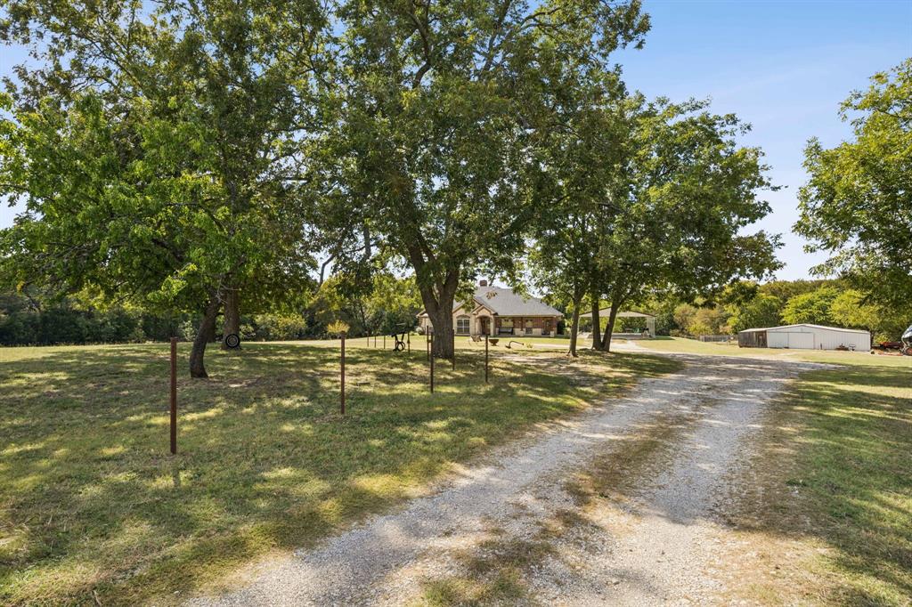 Experience wide-open living in this pristine 2,140 sqft, 3-bedroom, 2.5-bathroom home perfectly situated on over 6 ACRES of scenic, unrestricted land. Freshly painted throughout, this property combines timeless style with the freedom of country living. Enjoy the open living space equipped with an isokern fireplace that uses volcanic pumice material with a high insulation value & heat-reflective properties, leading to greater efficiency & cleaner burning for those cold winter nights. No city limits, no compromises. Outdoors, this property is a dream for anyone who loves space, self-sufficiency, or projects of any kind. A 30'x40' barn with water and electricity, a 15'x40' lean-to, and a 25'x40' powered workshop provide extraordinary capacity for equipment, hobbies, or livestock operations. The ag exemption and existing cattle setup keep taxes low while offering true agricultural potential. Cast a line in your own private fishing pond, or unwind beneath endless Texas skies. With 3 covered parking spaces and room to roam, this property delivers rural independence with modern livability.