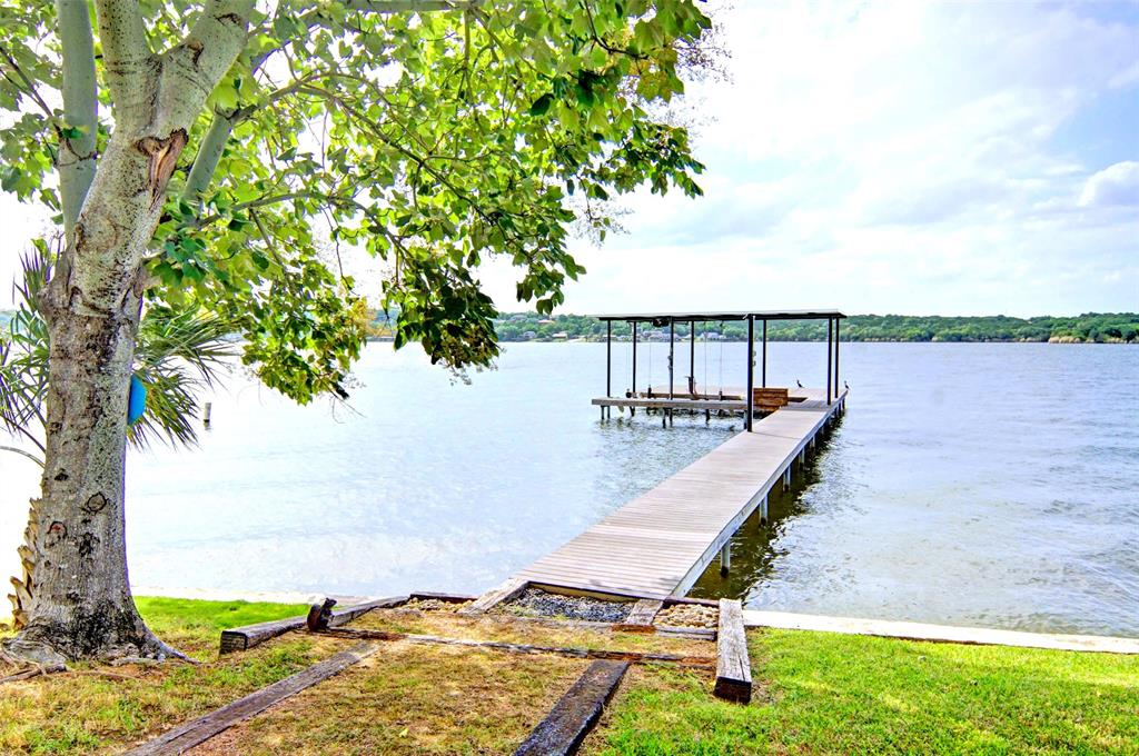 Welcome to this fabulous main body waterfront property with deep water, panoramic views, and incredible sunsets. This private oasis is situated at the end of a quiet cul-de-sac featuring mature trees and beautiful landscaping with irrigation from the lake. This property is not included in a HOA and is outside the city limits allowing for unrestricted enjoyment of this incredible lake Granbury retreat. Enjoy the bunk house and pavilion featuring a full outdoor kitchen and plenty of space for entertaining family and guests. Easy access to the water and boat dock with a retaining wall spaning across the 158 ft of water's edge ready for your true lake Granbury experience. The boat dock is perfect for parking your boat and watercraft with lots of deck space for fishing and hanging out on the water. Two 50 AMP RV hookups fresh water supply valves, and dump connections available. This is a rare chance to own your ideal lake Granbury retreat and make some unforgettable memories with family and friends. Bring the family and come look at this one, this is the lake property you have been dreaming of.