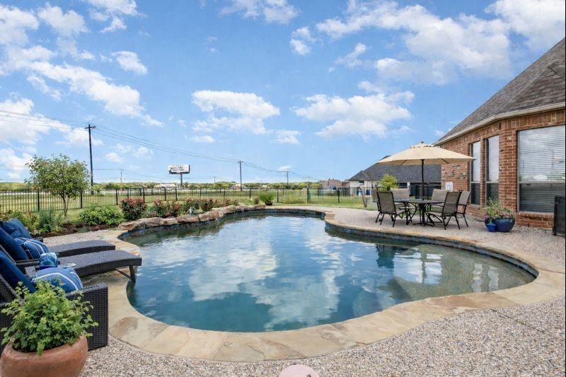 OWNER FINANCING AVAILABLE! Discover the perfect blend of luxury, privacy, and wide-open space in sought-after Chisholm Ranch Estates. Nestled on 1.5 acres, this stunning 4-bedroom, 4-bath home offers over 3,200 square feet of thoughtfully designed living space and an exceptional backyard retreat. The open-concept floor plan features soaring ceilings, abundant natural light, hardwood floors, and spacious living areas ideal for entertaining. The chef's kitchen is equipped with granite countertops, a large center island, double ovens, gas cooktop, ample cabinetry, and a walk-in pantry.
The private primary suite offers a spa-inspired bath with dual vanities, garden tub, separate shower, and walk-in closet. Upstairs, a versatile game room provides additional space for recreation, media, or a home office. Step outside to your own backyard oasis featuring a sparkling saltwater pool, expansive covered patio, and plenty of room to relax, entertain, or enjoy peaceful Texas sunsets. A long driveway and oversized 3-car garage provide ample parking and storage. Enjoy the tranquility of country-style living while remaining just minutes from downtown Rockwall, shopping, dining, and highly rated Rockwall ISD schools. Rare owner-financing opportunity available—contact listing agent for details. This property qualifies for a lender paid 2-1 buy down for qualified buyers, ask agent for info!
