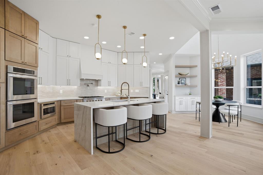 STUNNING organic modern home, thoughtfully redesigned for everyday living and effortless entertaining - over 3,100 sq ft of the living space is downstairs. New wide plank white oak flooring, all new windows, dramatic double iron entry doors and EXPANSIVE sliding glass doors that open seamlessly to the backyard retreat complete with a built-in grill, spacious entertaining spaces and pond views. The oversized chef's kitchen is the centerpiece of the home, featuring a 60 cubic ft refrigerator, double ovens, chef-grade gas cooktop, flowing to a huge family room with wet bar and ice-maker. Additionally there is a large dining with butlers pantry and living area accented with beautiful wood beams and a fireplace for warmth and sophistication. The spacious primary suite has a sitting area and access to the backyard and primary bath and closet is luxurious. Even the utility room is elevated! Upstairs there are 2 large ensuite bedrooms and a huge covered balcony. There is no carpet. EV charger in garage. This home is a golf cart away from Stonebridge Country Club and Adriatica as well as Bennett Elementary and Stonebridge Ranch many amenities including trails, pools, pickleball and tennis courts.
