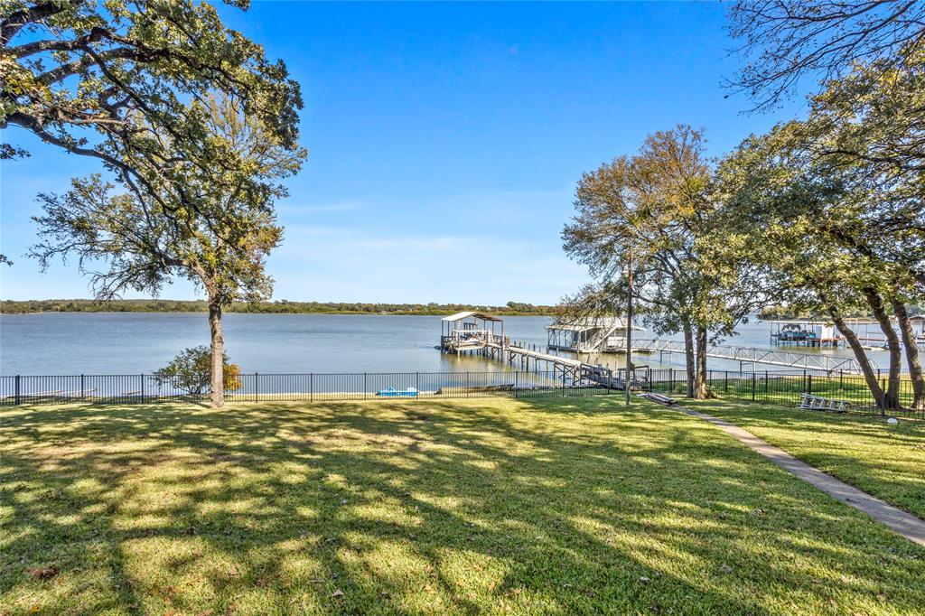 Welcome to your ideal lakefront retreat — a beautifully situated home on 1.4 acres with a large backyard, stunning mature oak trees, and multiple climate-controlled buildings that offer unmatched versatility. This 2,800 sq ft lake house delivers comfort, space, and the perfect setting for year-round lake living.
Inside the home, a bright floor plan captures wide water views from the main living areas, while the spacious back porch provides the perfect place to unwind and enjoy quiet mornings or sunset evenings overlooking the lake.
This property stands out with multiple high-quality outbuildings. The 1,200 sq ft insulated, climate-controlled shop is ideal for vehicles, woodworking, hobbies or storage. Additionally, a fully finished 12×16 climate-controlled building features cabinets, a sink, and a fridge — making it ideal as a guest room, private office, hobby studio, bunkhouse, or even an additional sleeping space if desired.
Out by the water, the covered dock (currently being re-covered for a fresh new finish) provides easy, direct lake access for boating, fishing, swimming, and relaxation.
The expansive 1.4-acre lot offers a large, open backyard perfect for gatherings, pets, outdoor games, gardens, or future additions. Plenty of parking means you can comfortably accommodate guests, trailers, boats, and equipment.